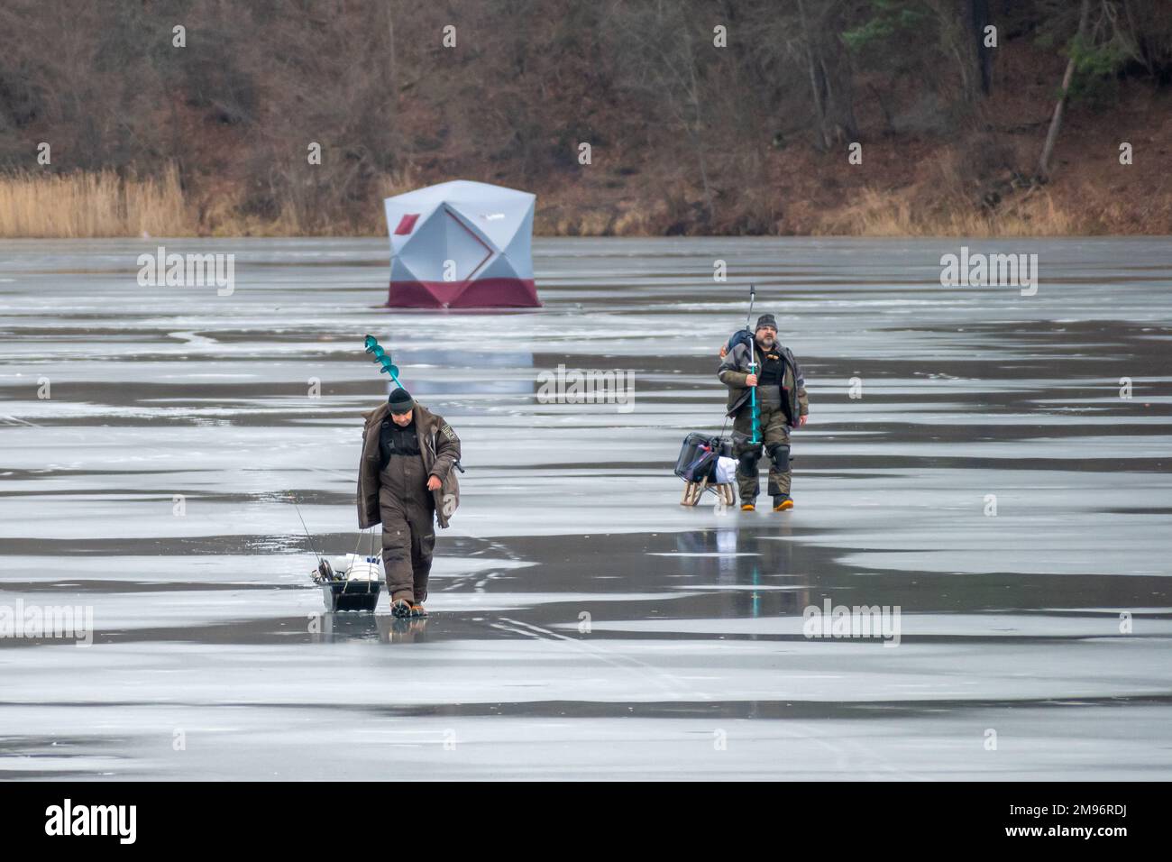 Fishermen leaving after fishing on a frozen lake in winter with fishing