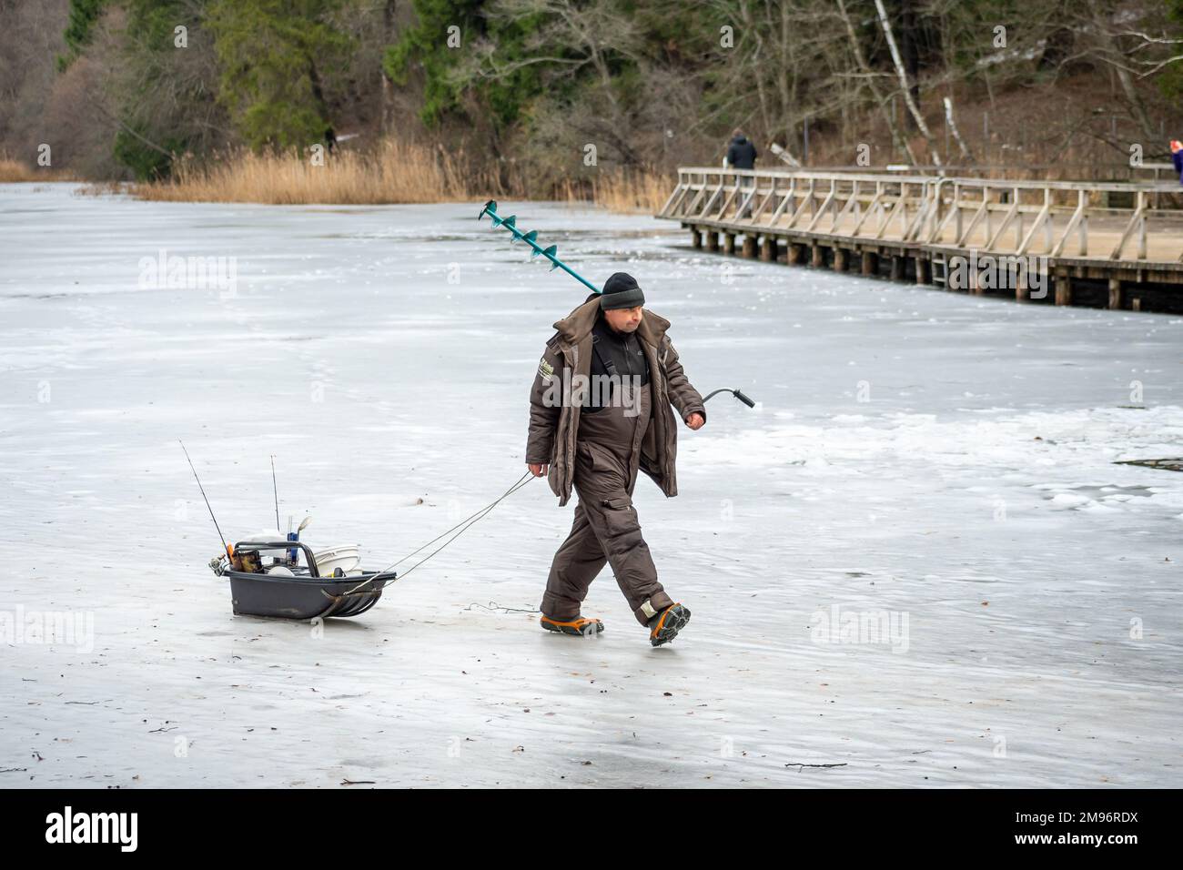 Fisherman leaving after fishing on a frozen lake in winter with fishing