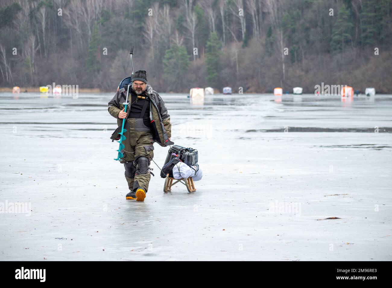 Fisherman fishing on a frozen lake in winter with fishing pole or rod