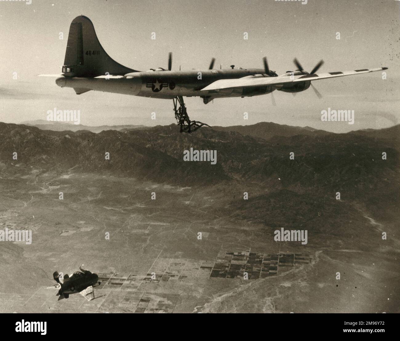 A McDonnell XP-85 Goblin approaching modified B-29B-65-BA for hook-up to a trapeze lowered from the rear bomb-bay. Stock Photo