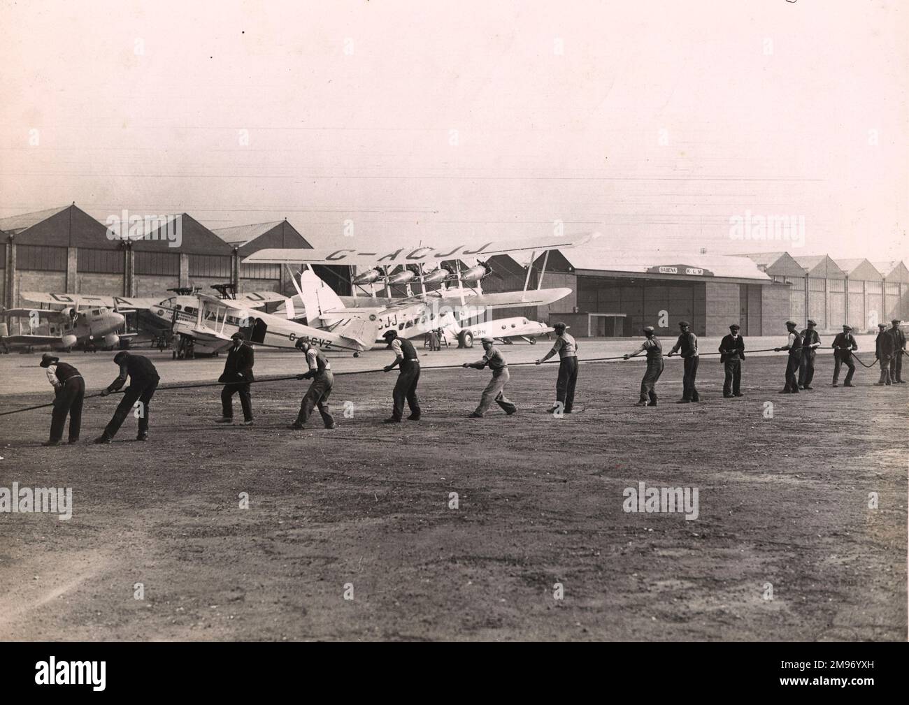 Engineers laying a new electric cable at Croydon Airport in March 1935. Among the aircraft in the background are Boulton & Paul P71A, G-ACOX, Boadicea, of Imperial Airways; Short L17, G-ACJJ, Scylla; de Havilland DH86, G-ACVZ, Jupiter, of Railway Air Services and Avro 652, G-ACRN, Ava. Stock Photo