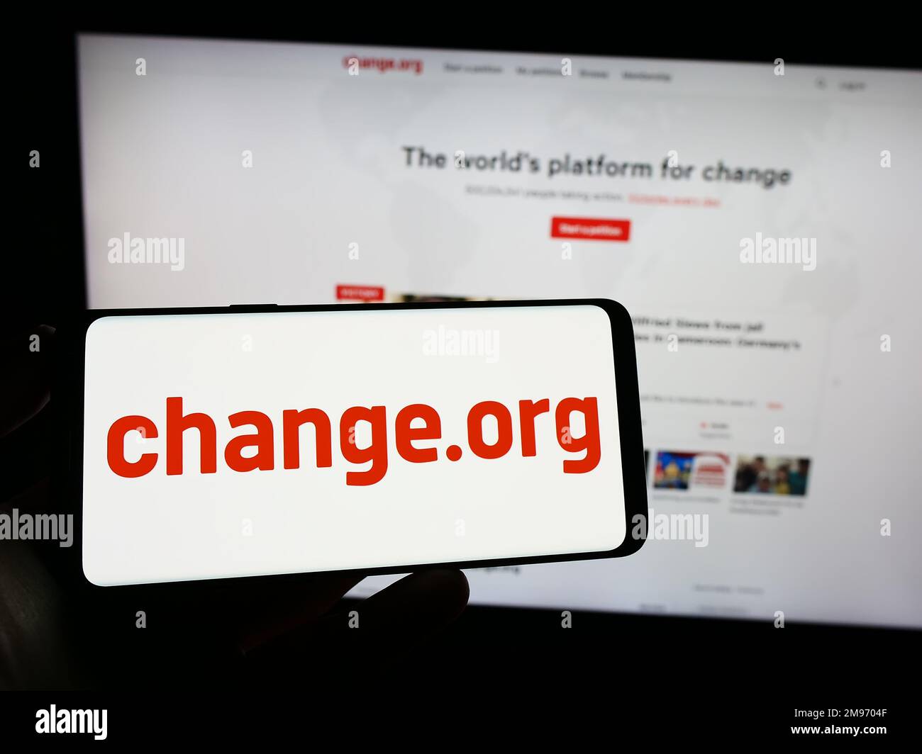 Person holding smartphone with logo of US petition platform Change.org PBC on screen in front of website. Focus on phone display. Stock Photo