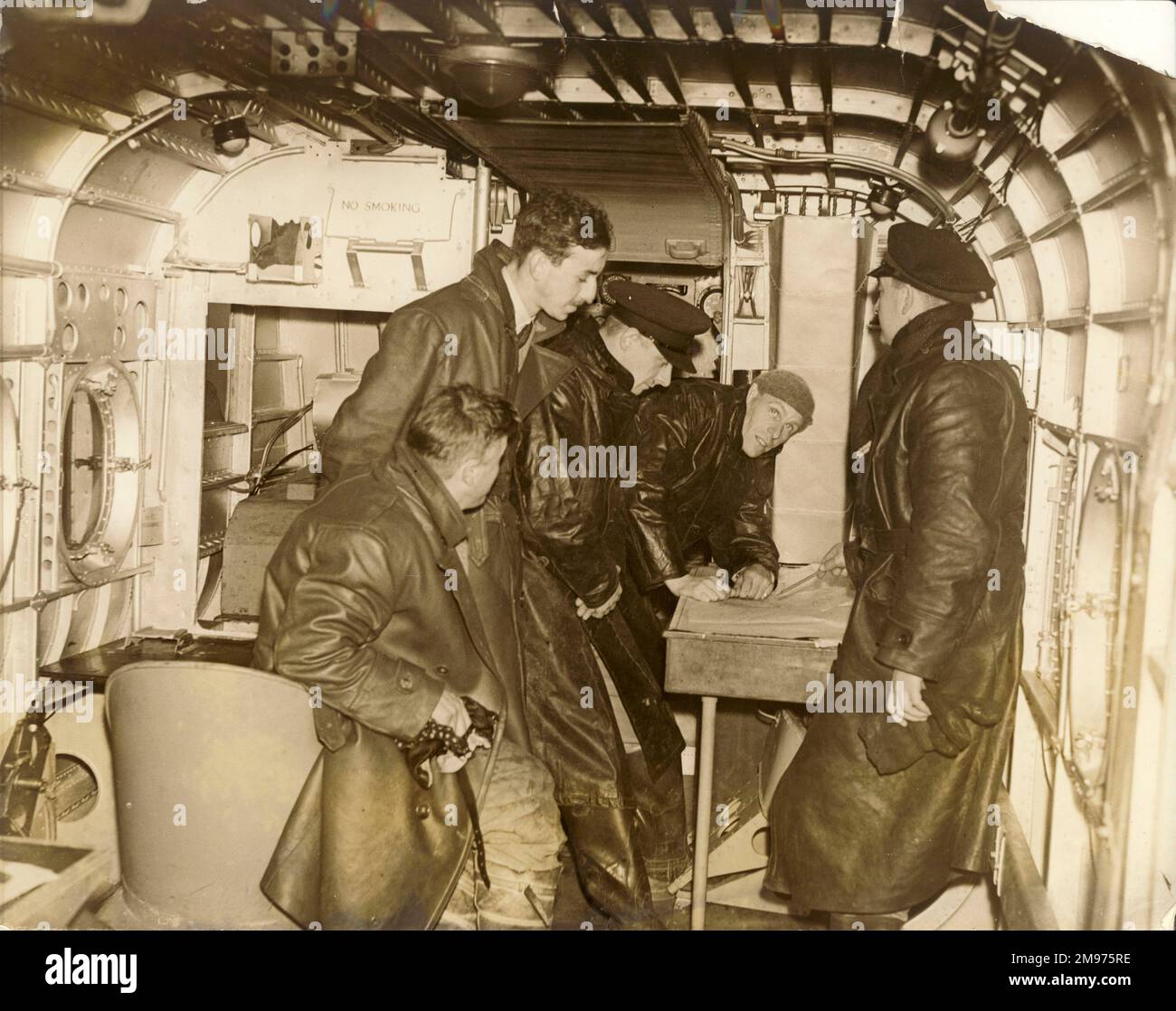 Receiving instructions on flying boats in the cabin of a Short S8/8 Rangoon flying boat at The Air University, Hamble, Hants. From right: Seaplane Instructor Flt Lt Pascoe, First Officer J.F. Nicholas (leaning on table) and First Officer F.D. Smith, with two other students. [see also 56011039] Stock Photo
