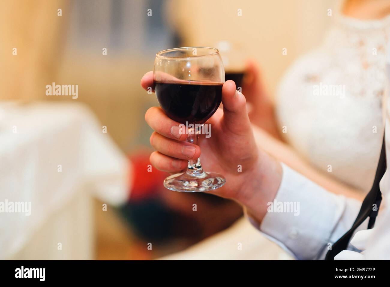 glass of red wine in the hand of a man close-up with a blurred background Stock Photo