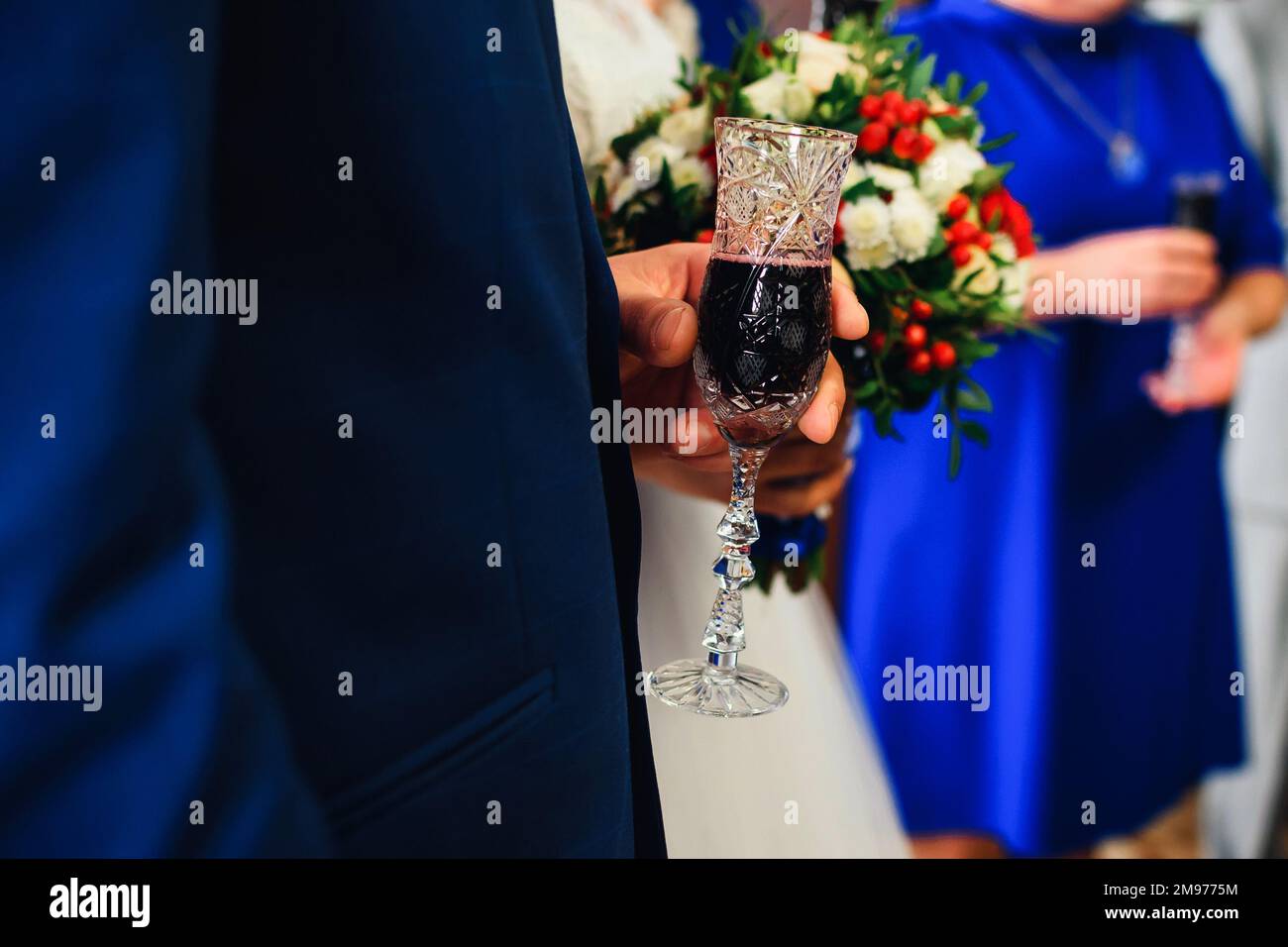 glass of red champagne in the hand of the groom at the wedding close-up Stock Photo