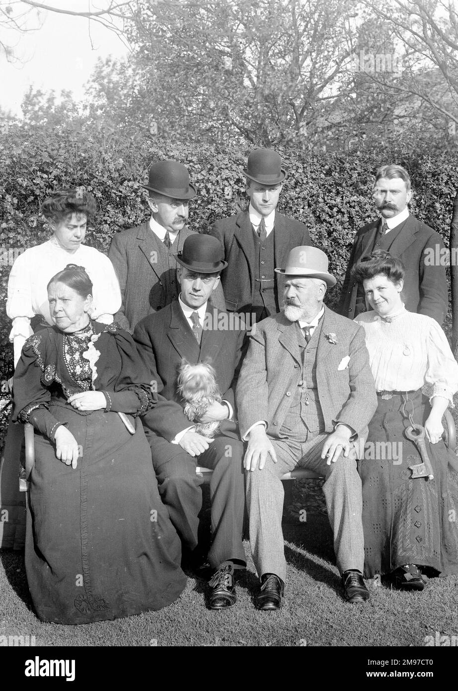Edwardian group in the garden of Strathclyde, Offerton Road, Stockport. Standing with his sister and brothers is James Johnson Battersby who survived the Lusitania sinking ten years later. The seated older couple are the hat manufacturer William Battersbyand his wife Mary. Even for a group photograph taken by a family member it seems hats were almost obligatory, and note the enormous decorative key adorning Mrs Allpegarth, seated front right. Stock Photo