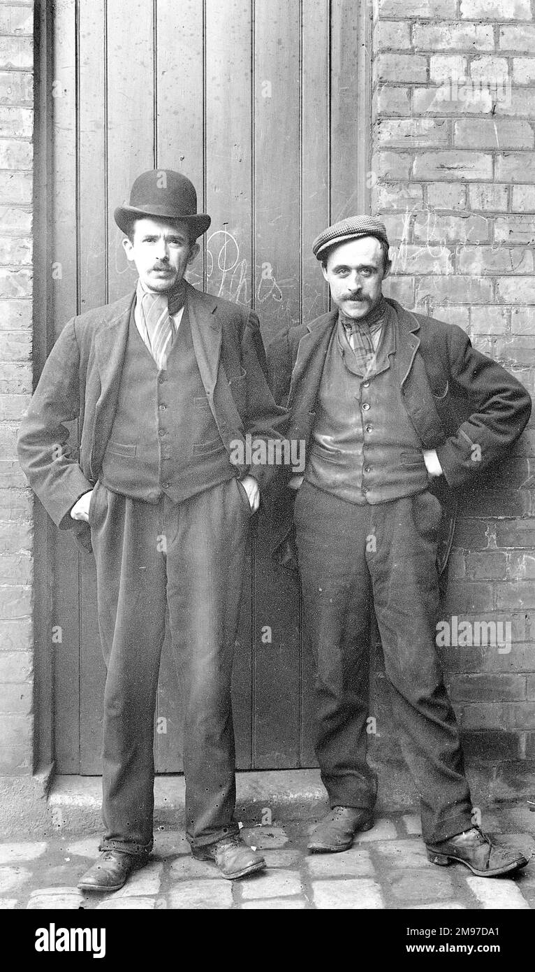 Ernest Battersby took a number of photogrpahs of employees at the family hatworks in Stockport, and noted their names as well. It is not specified which man is which, but the census record show that both worked as 'Plankers', partof the felt production  process. In 1911 Walter Moult was aged 40, married with three children in Charles Street, Stockport, and in the same year James Fidler was 38, married but boarding alone at Buckingham Street, Stockport. This makes the men about 33 and 35 years old and they illustrate the clothing typical of a factory worker at the time. Stock Photo