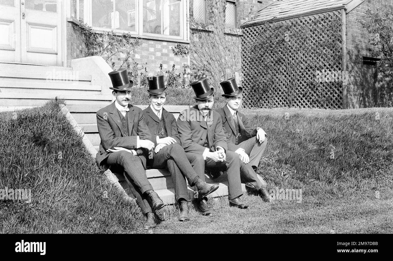 Four well dressed Edwardian men named by the photographer - on the left is Ernest Battersby, the photographer, and their left is his brother James Johnson Battersby. The other two are named as Forster and Dickenson. They are sitting onthe steaps of the Battersby family home in Stockport, and their dress will reflect their upper-middle class status at the time. Stock Photo