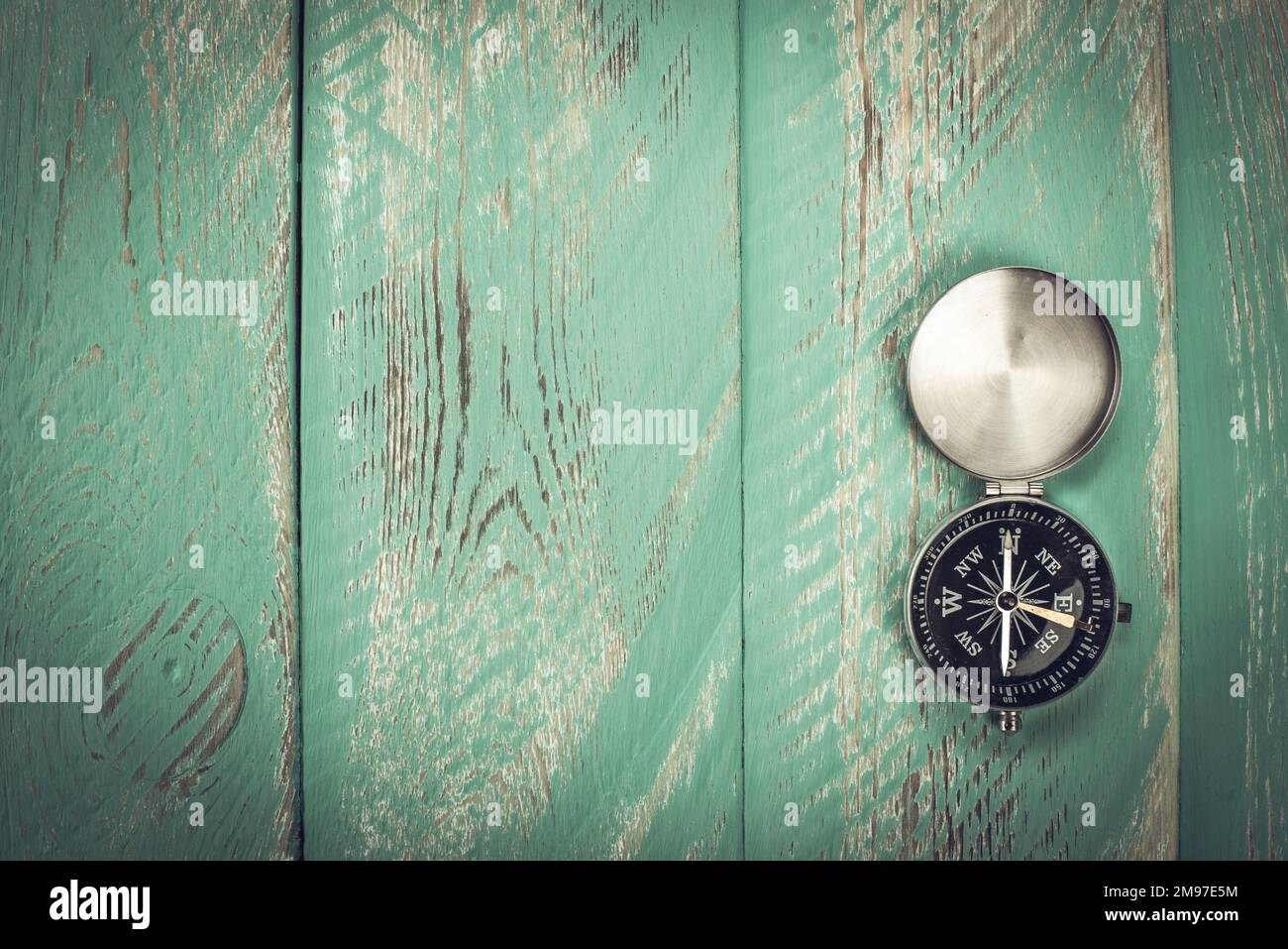Compass with an open lid on a vintage old table. Stock Photo