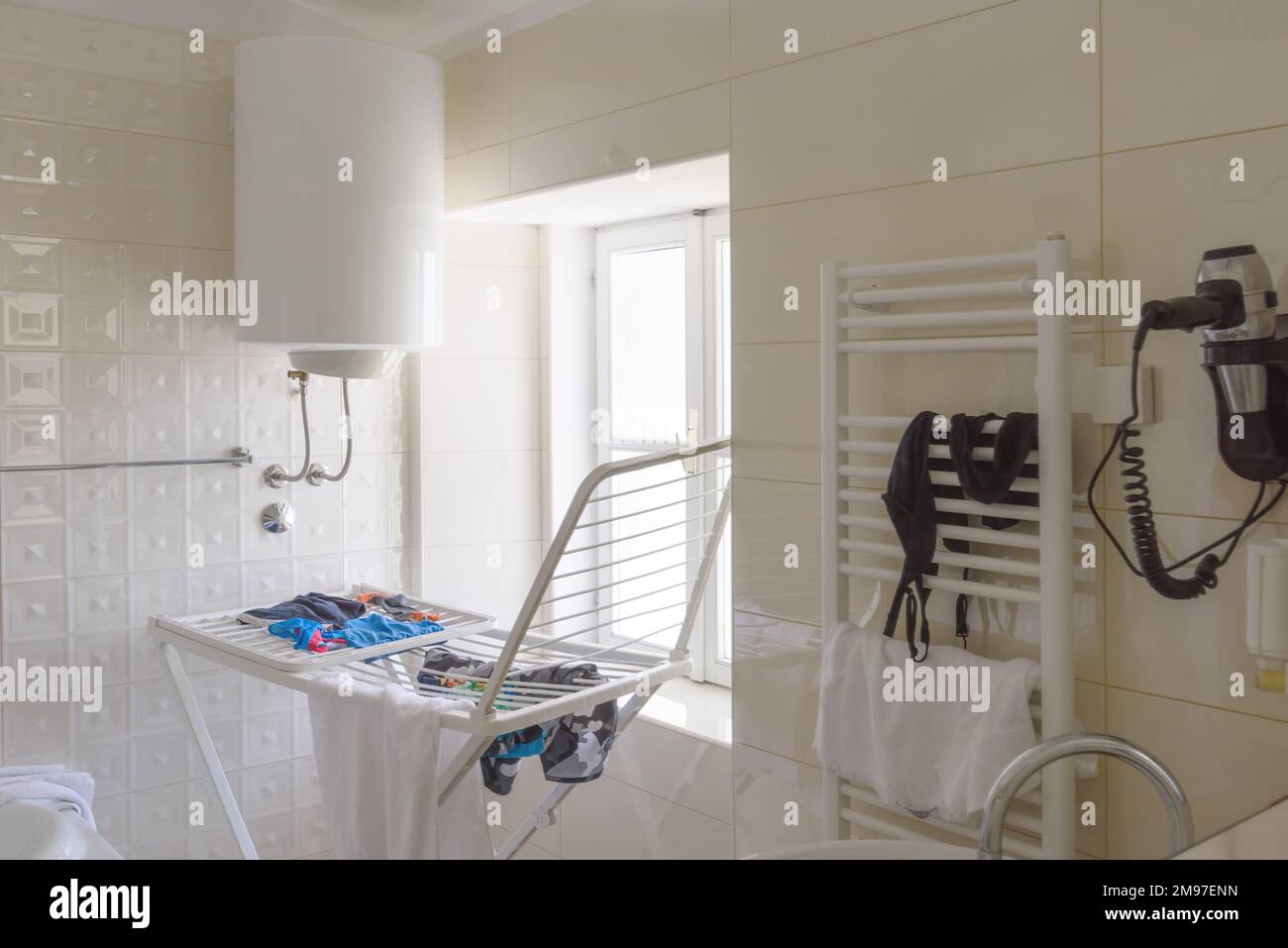 Cluttered bathroom with clothes on drying rack, selective focus Stock Photo