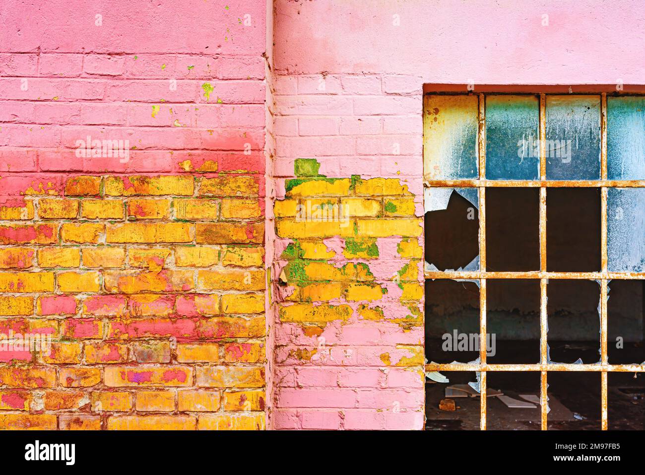 Old grid windows with broken glass on exterior wall of an old abandoned