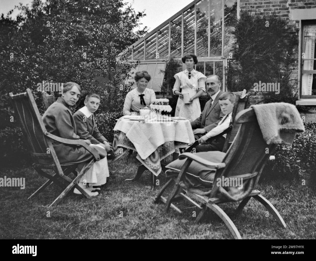 Family group of six enjoying afternoon tea in a garden. Stock Photo