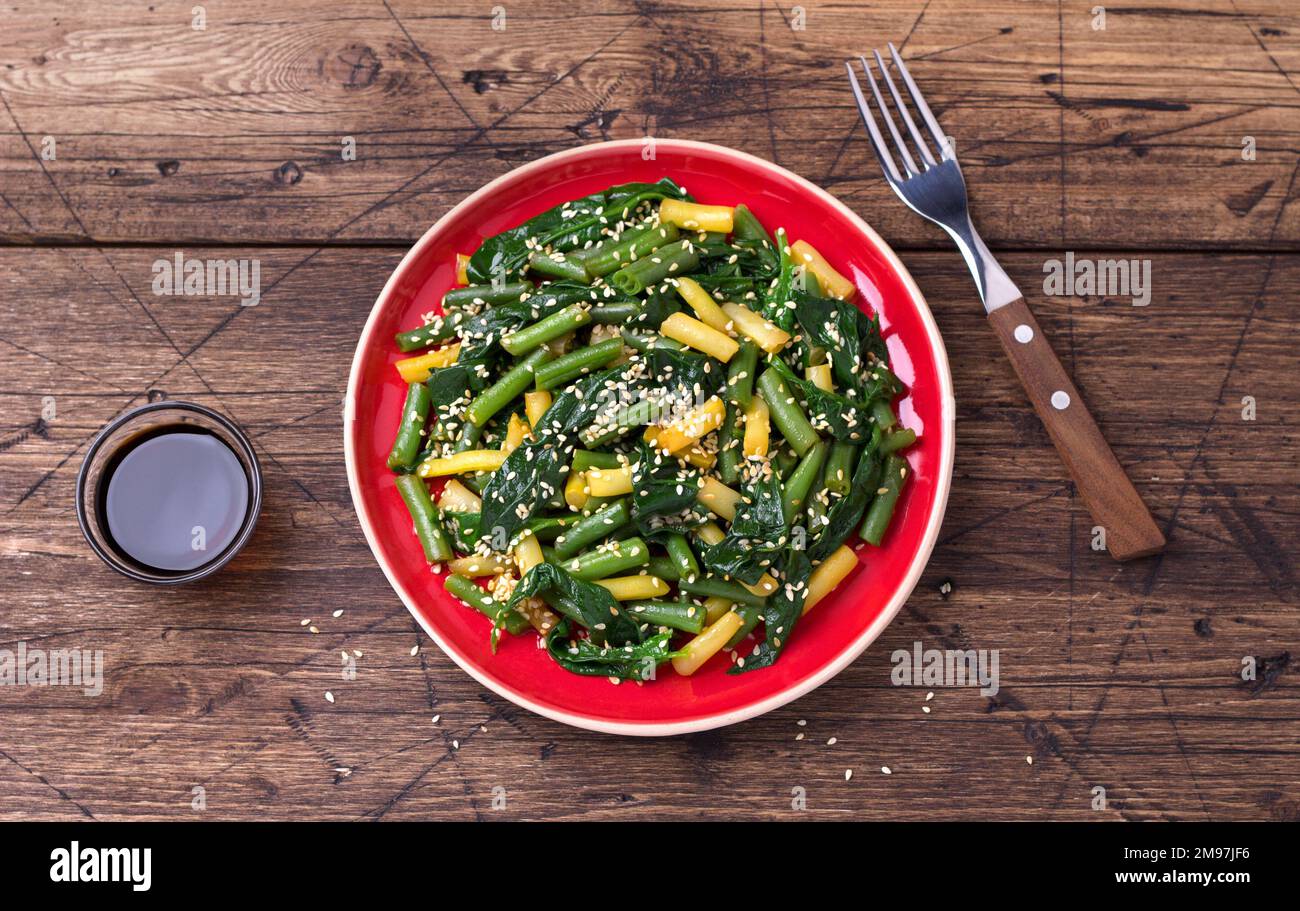 Green and yellow beans with spinach, sesame seeds and soy sauce on wooden table, top view Stock Photo