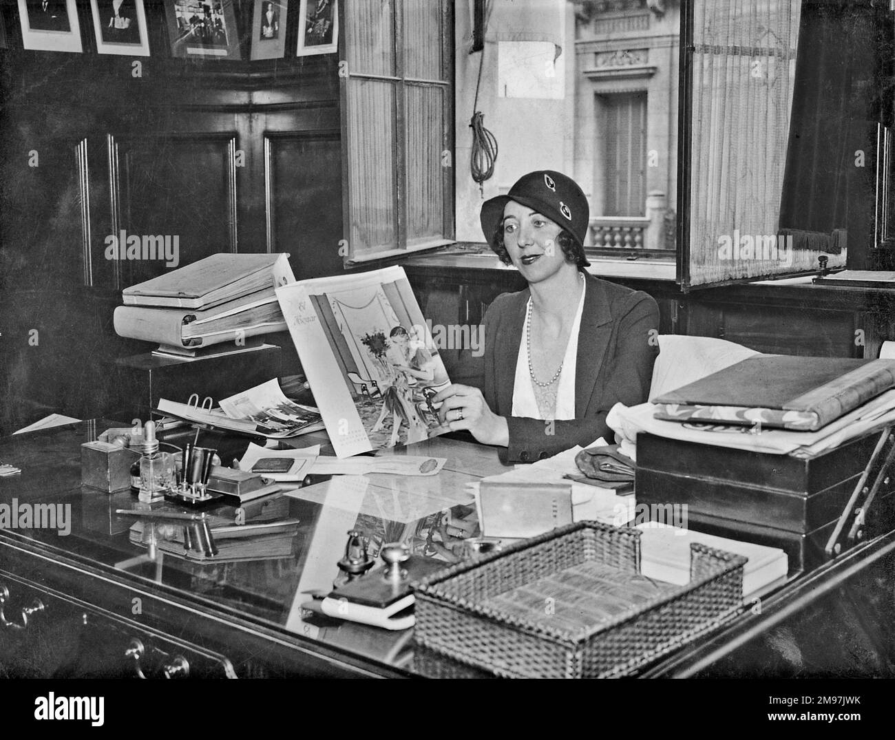 Fashionable woman sitting at a desk in an office. Stock Photo