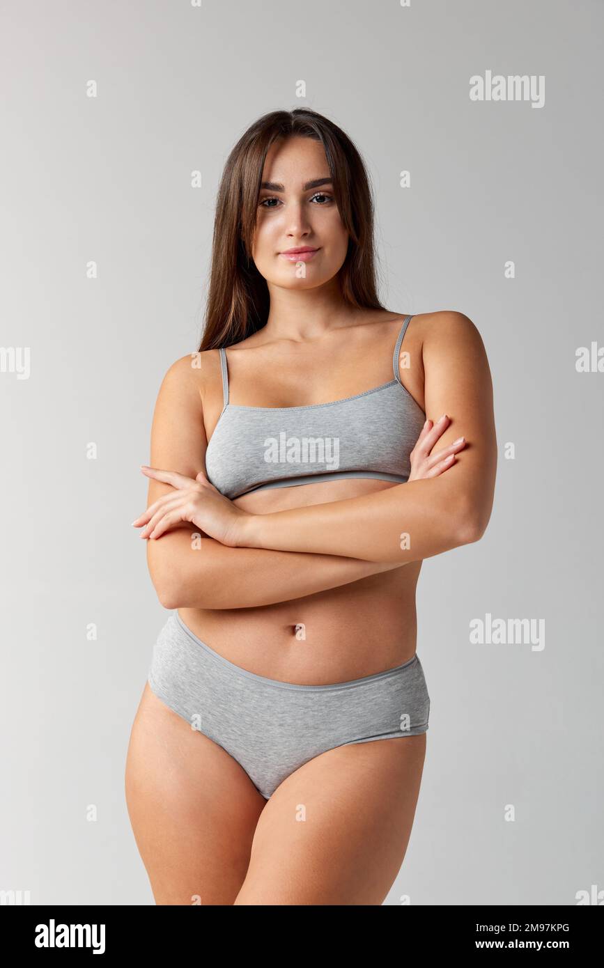 Well-being. Portrait of young beautiful girl posing in underwear over grey studio background. Concept of body and skin care, fitness Stock Photo