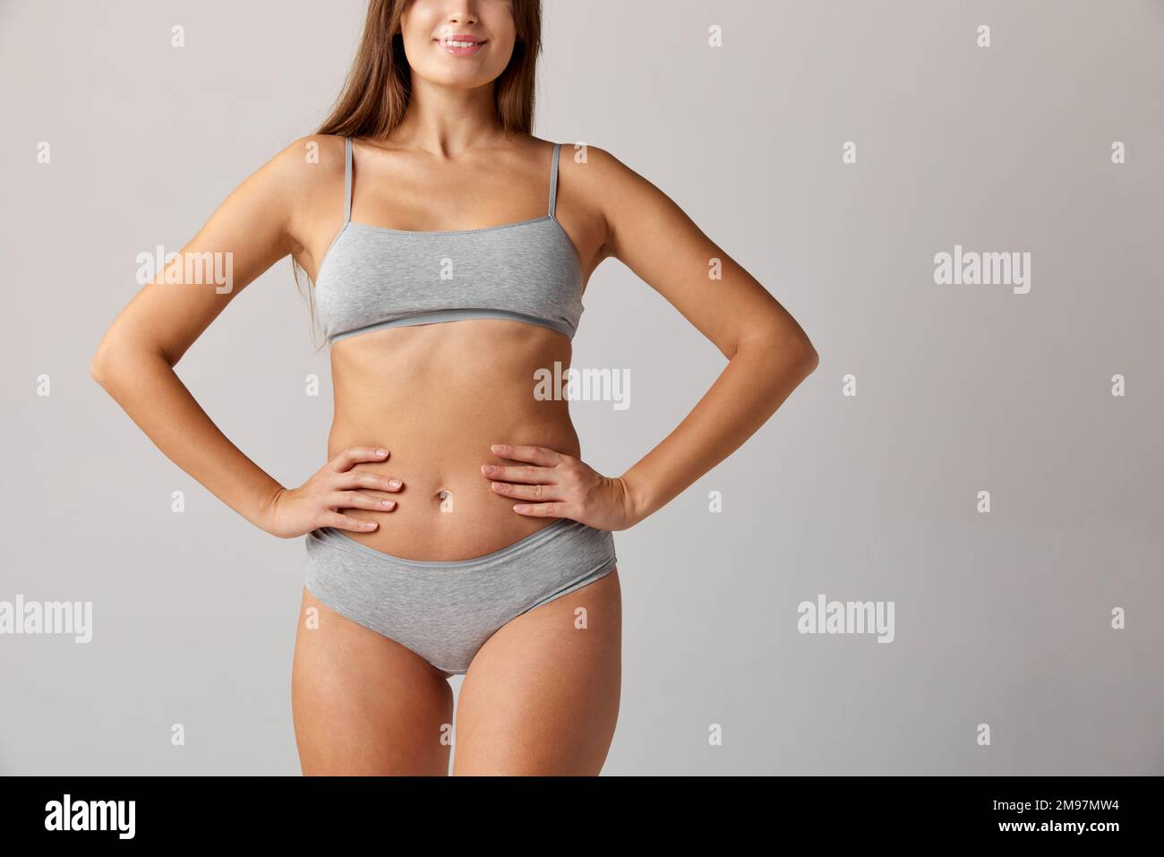 Cropped image of slim female body, breast, belly and buttocks in cotton underwear over grey studio background. Concept of body and skin care, fitness Stock Photo