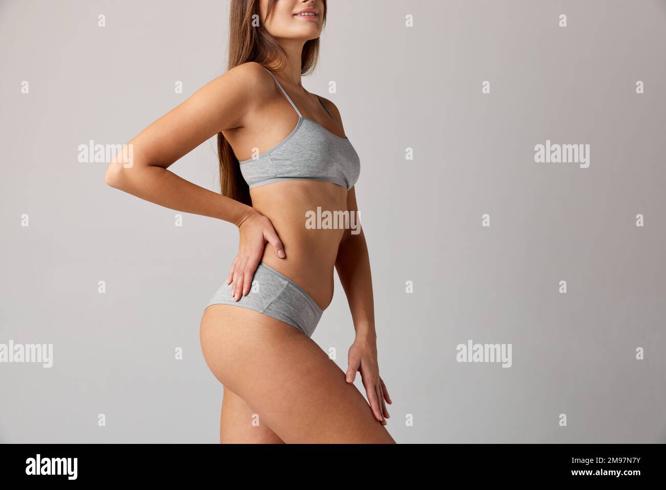 Cropped image of slim, fit female body, breast, belly and buttocks in cotton underwear over grey studio background. Concept of body and skin care Stock Photo