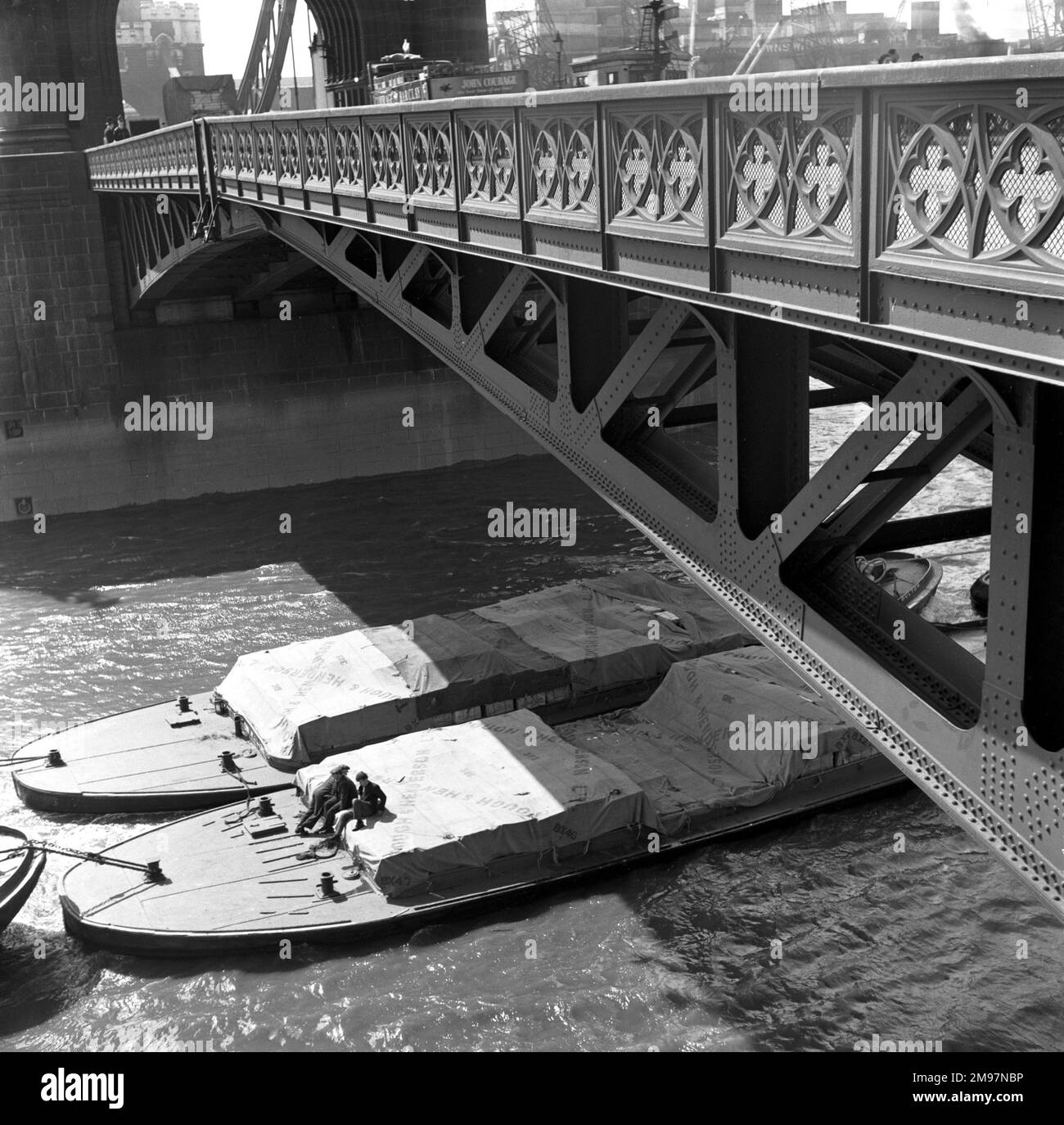 River barges and dockworkers towed under Tower Bridge, London. Stock Photo
