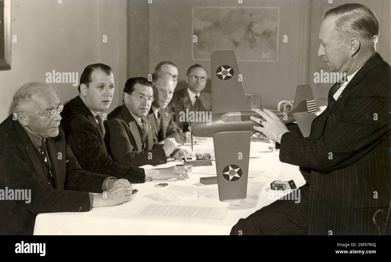 Leroy Randle Grumman (right), 1895-1982, co-founder and President of Grumman Aircraft Engineering Corporation, shows a group of radio commentators a scale model of a Grumman Wildcat fighter. From left: H.V. Kaltenborn, NBC; Johannes Steel, WMCA; C. Saerchinger, NBC; Paul Schubert, Mutual; Waverley Root, WINS and I. Howe, Columbia. Stock Photo