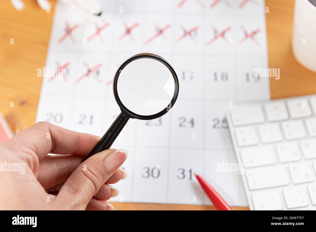 A hand with a magnifying glass examines the calendar and reminders for
