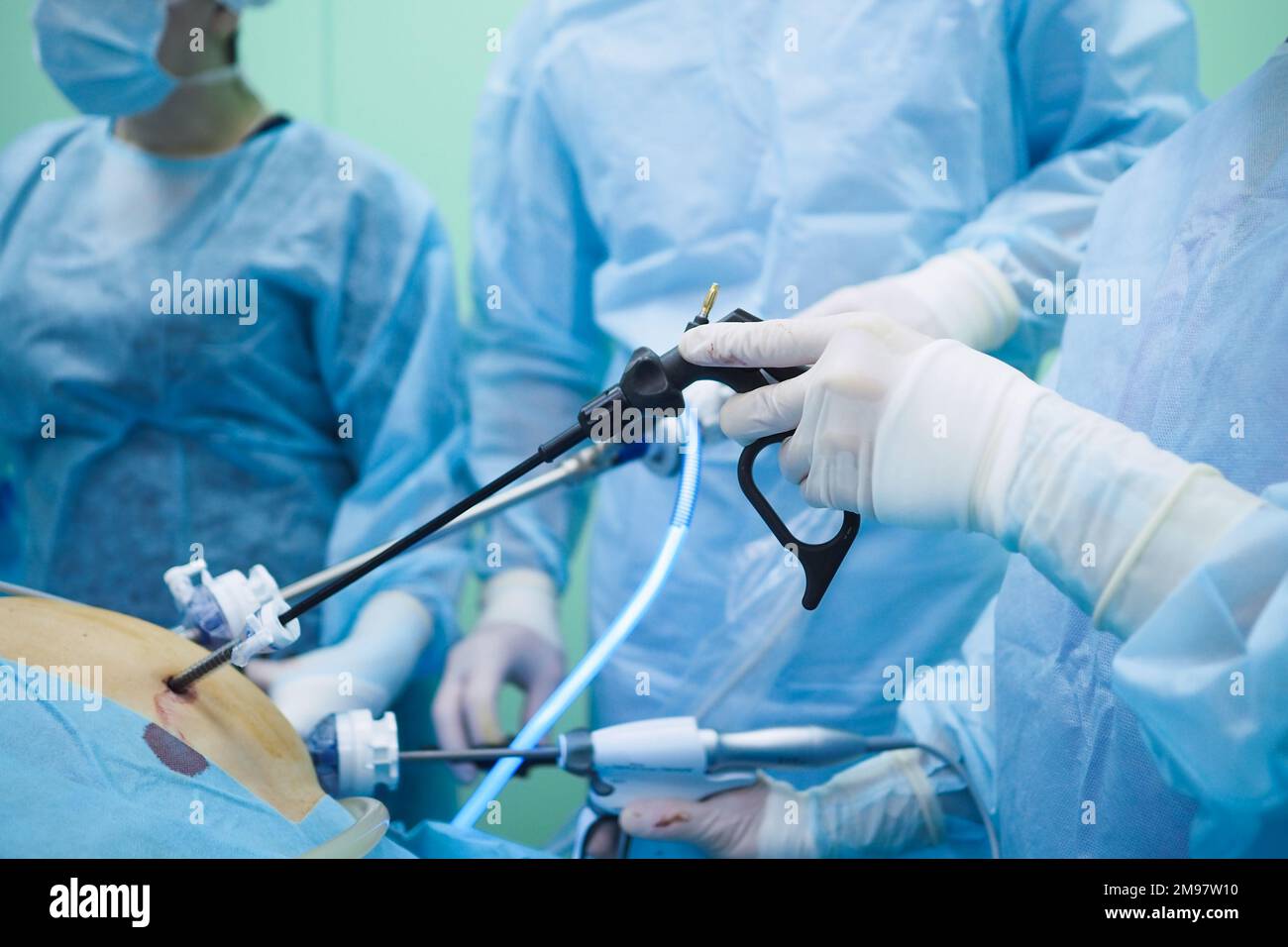 Laparoscopic surgical instruments in the hands of surgeons. Selective focus. Hands of surgeons in sterile gloves during surgery. Stock Photo