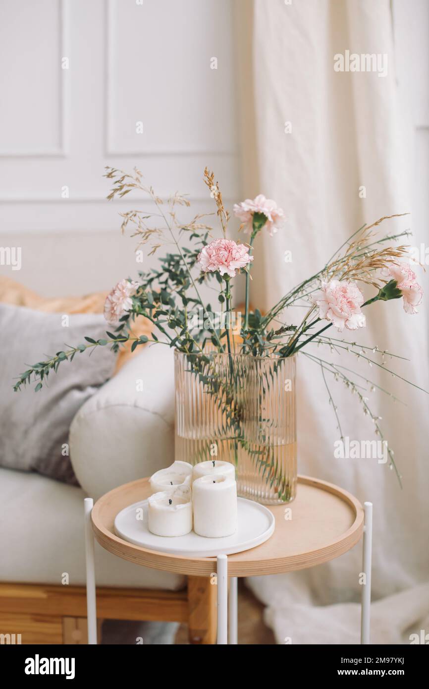 Bunch of flowers and candles on a side table next to a sofa Stock Photo