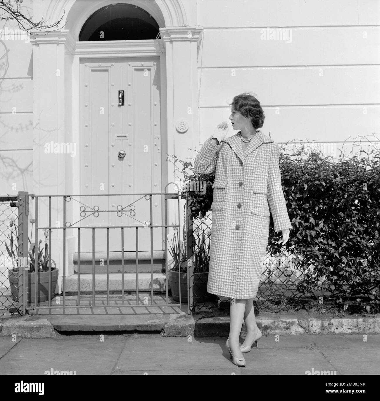 Advertisement for Burberry overcoats -- female model posing outside Georgian style house. Stock Photo