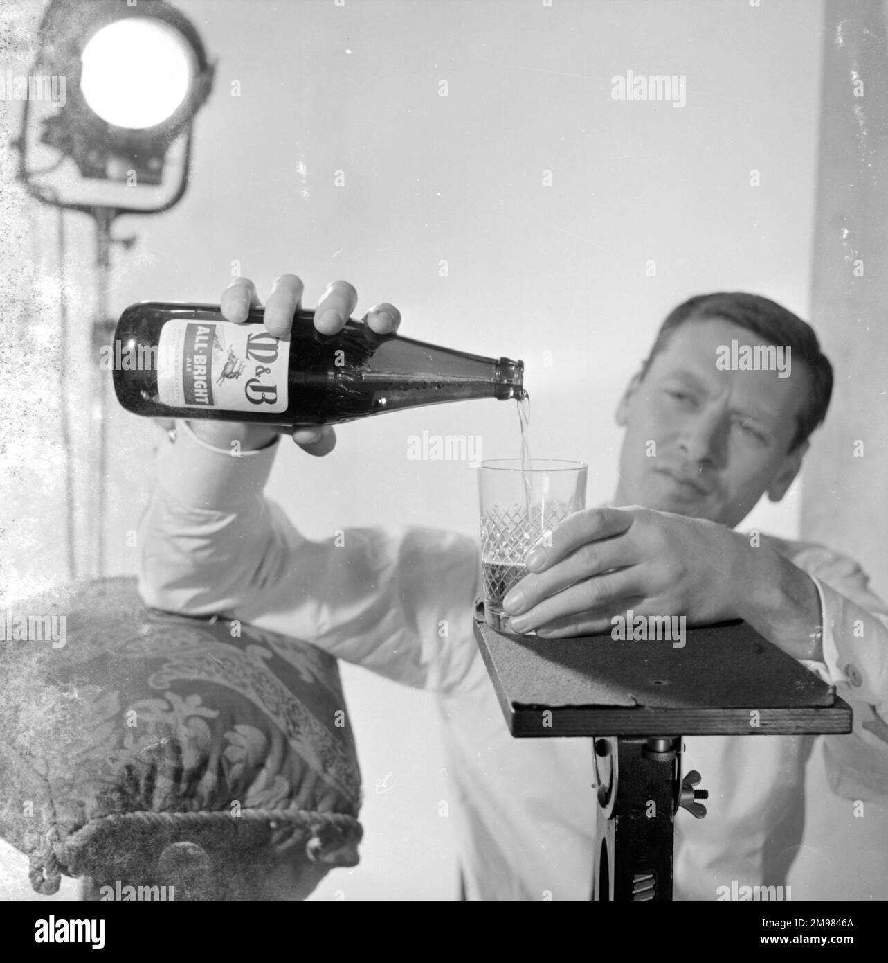 Advertisement for M&B All Bright beer male model pouring beer from a