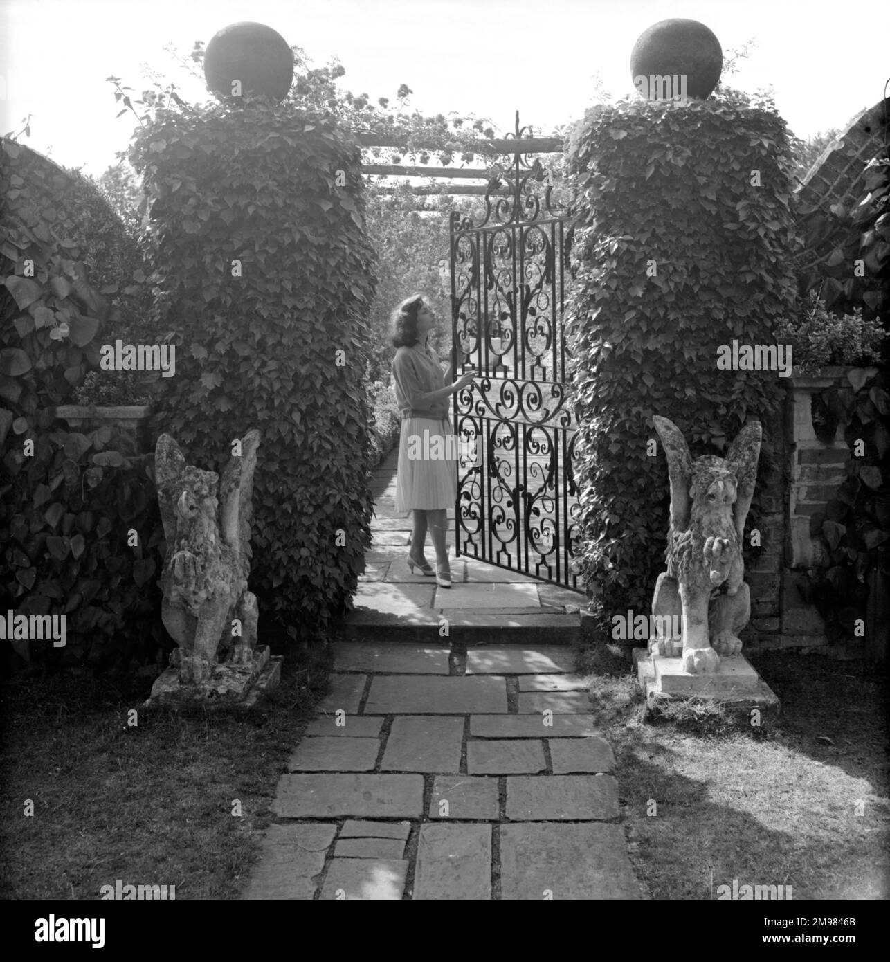 Wrought iron gate in a garden with female model. Stock Photo