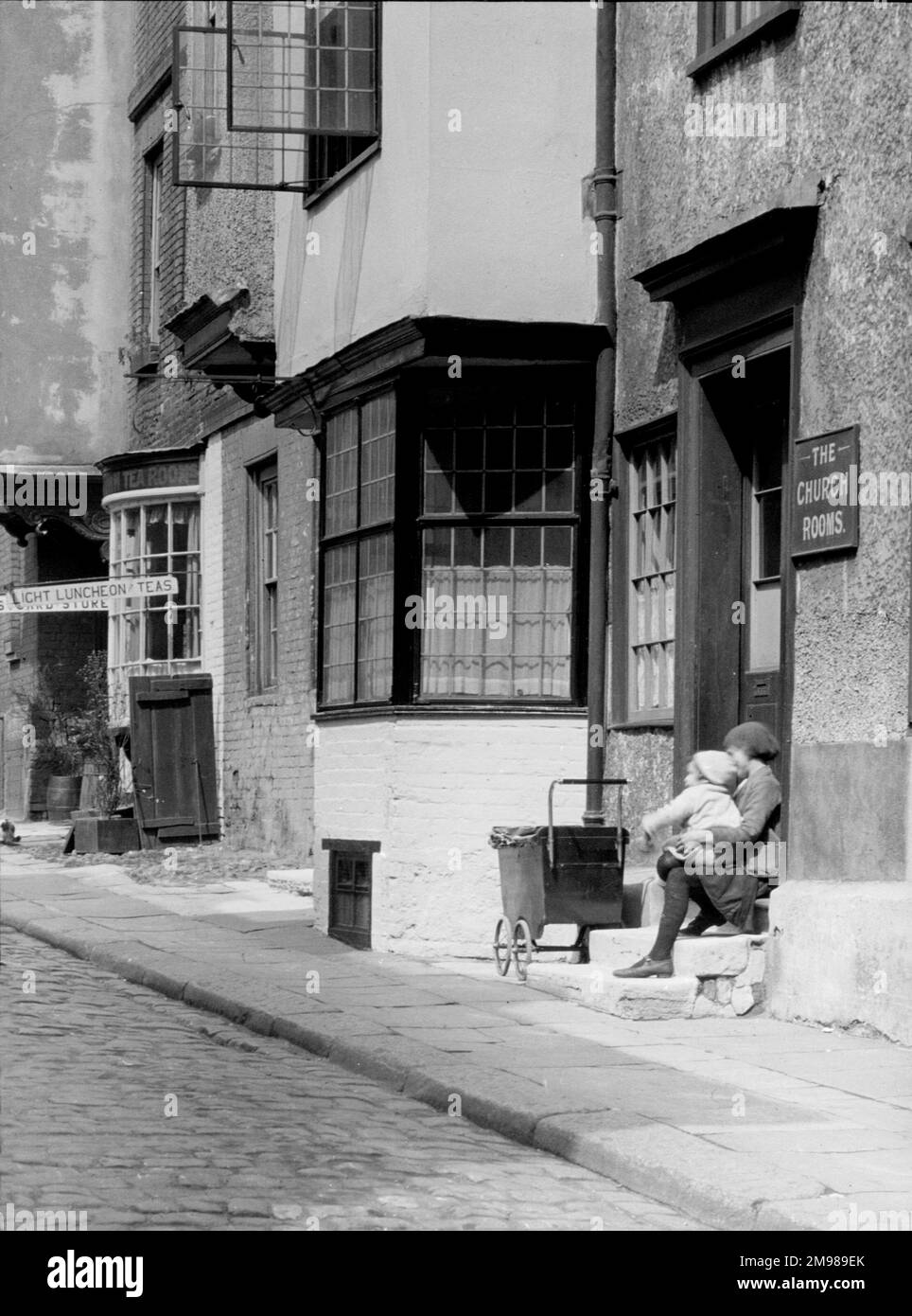 Two children with a pram, sitting on a step of the Church Rooms Stock