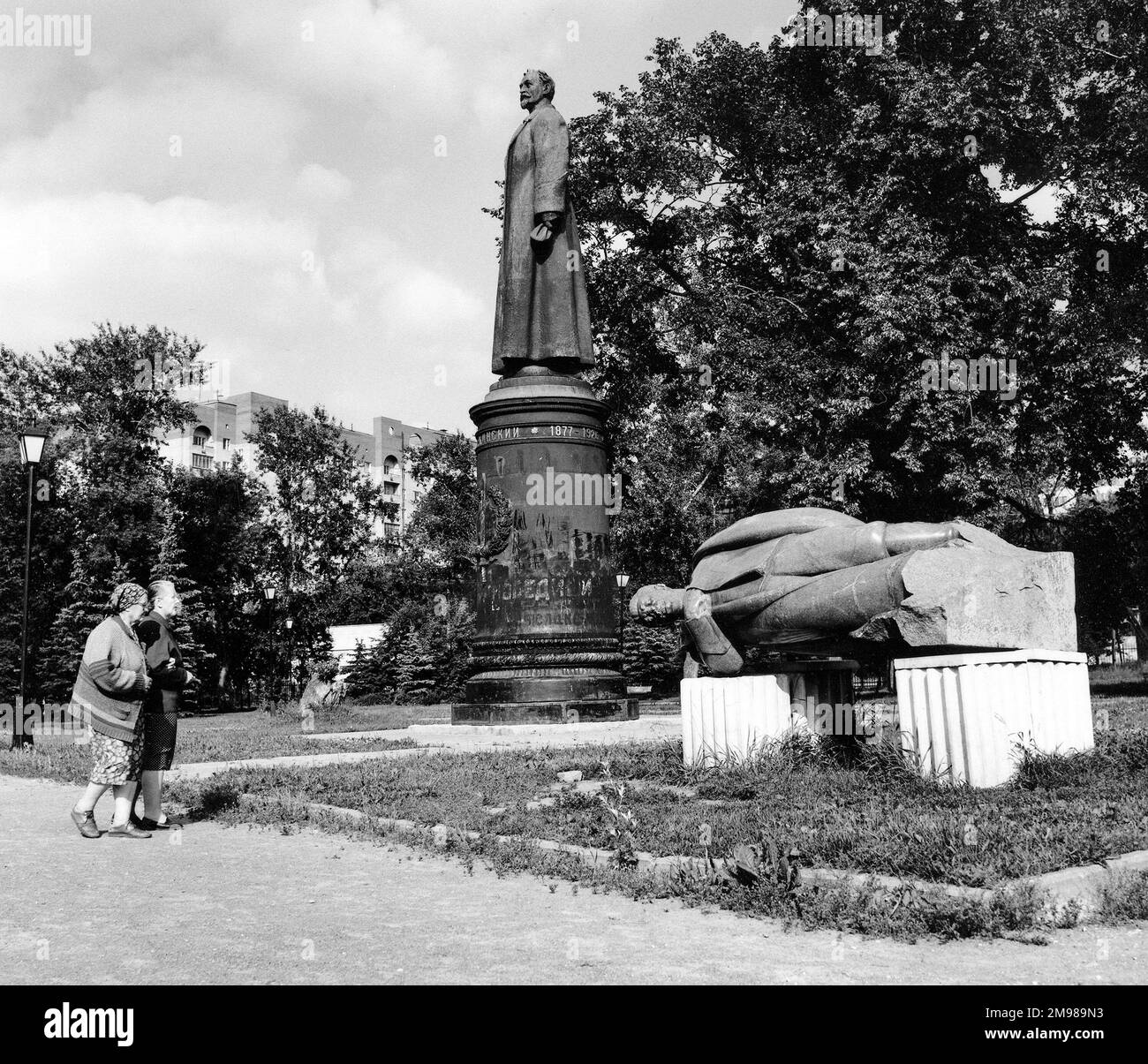 Two women view statues in the Muzeon Sculpture Park, Moscow, Russia. In the centre is a statue of Felix Dzerzhinsky (1877-1926), Polish-Russian agitator and head of the secret police. The statue on the right, lying on its side, appears to be of Josef Stalin. Stock Photo