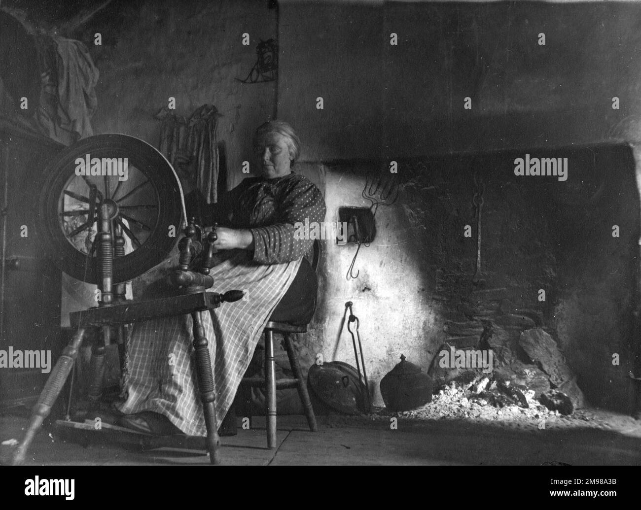 Woman in her cottage spinning wool in Glen Columbkille (Glencolmcille, Gleann Cholm Cille), County Donegal, north-west Ireland. Stock Photo