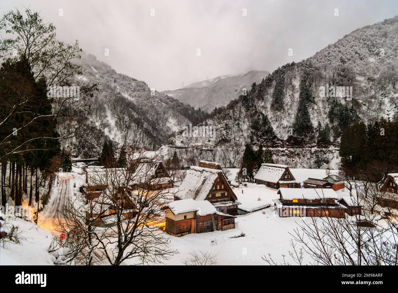 Lights on in snowy UNESCO World Heritage village in mountain landscape at dawn Stock Photo
