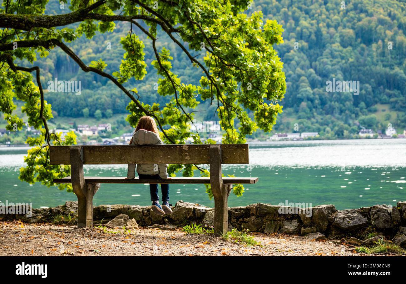 Little girl sitting on the bench and looking on the river scenery Stock ...