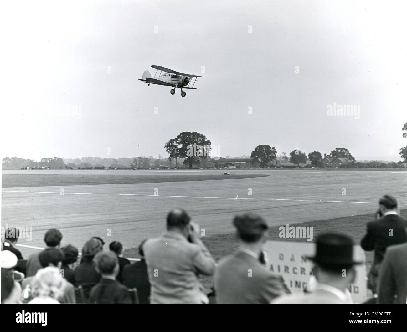 Gloster Gladiator, G-AMRK, gives a low flypast at the 1956 Royal Aeronautical Society Garden Party at Wisley on 15 July. Stock Photo