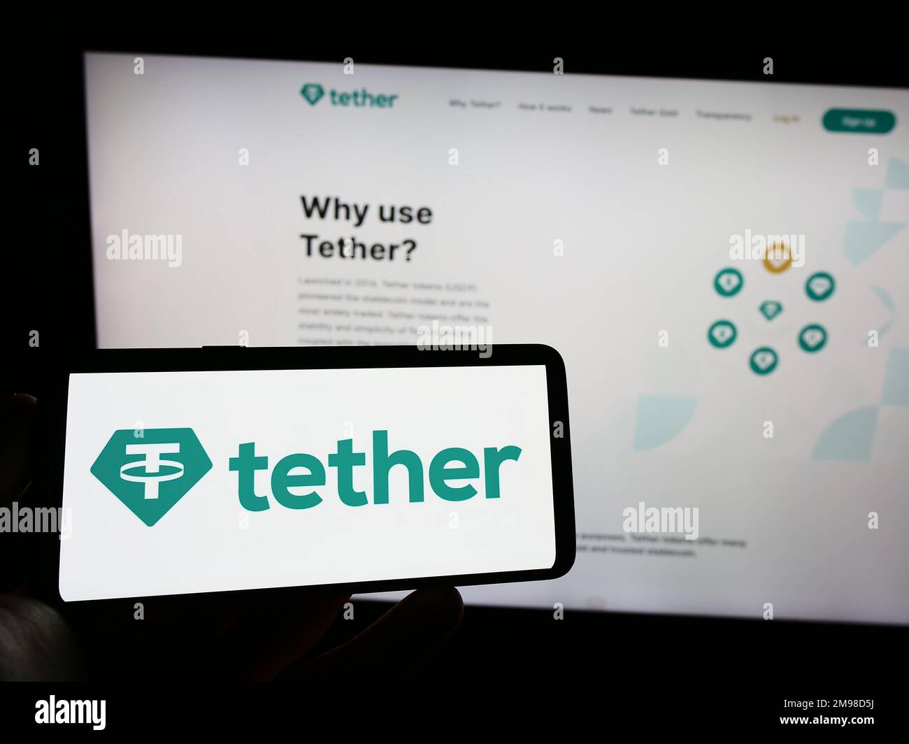 Person holding smartphone with logo of crypto company Tether Operations Limited on screen in front of website. Focus on phone display. Stock Photo