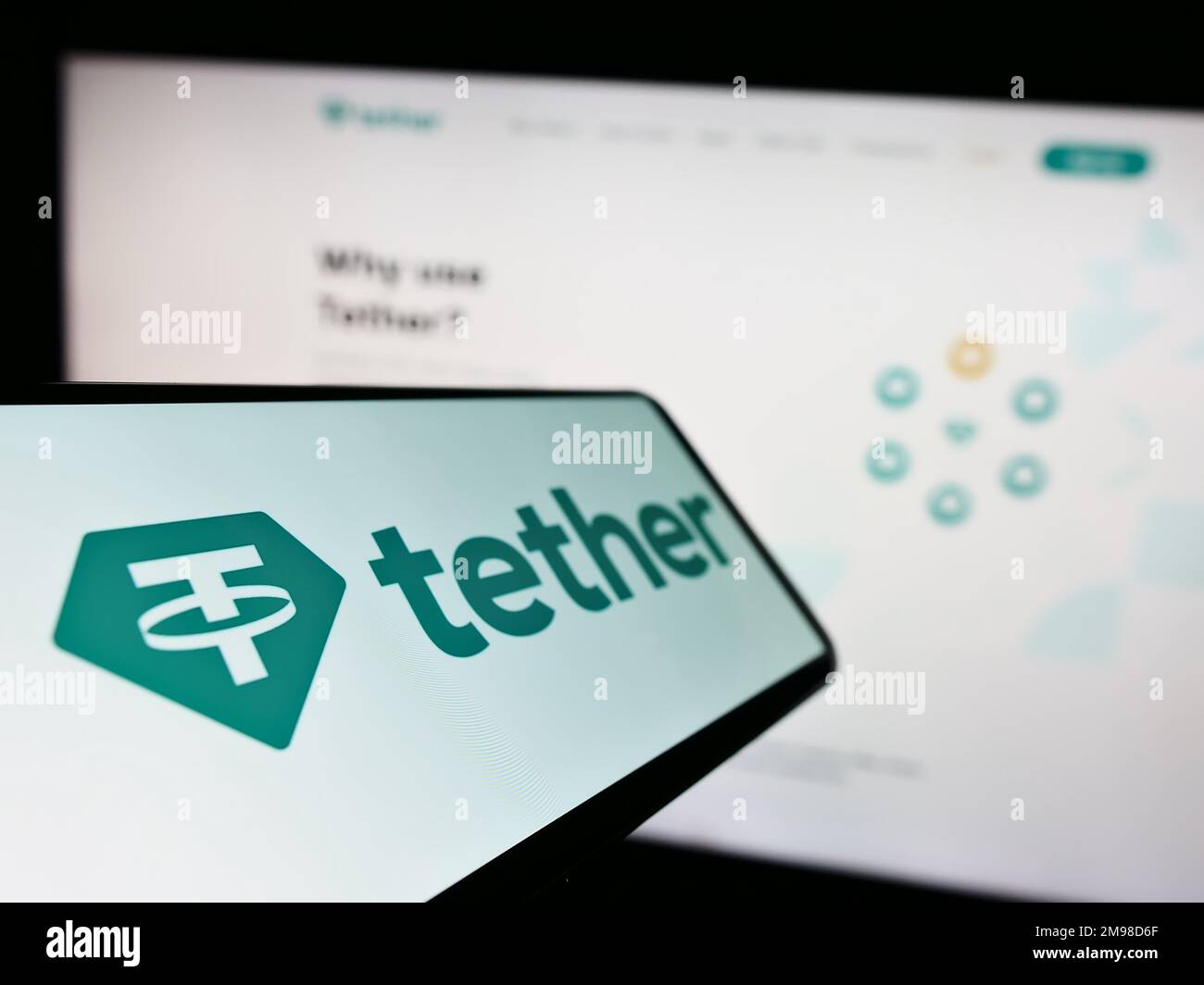 Mobile phone with logo of crypto company Tether Operations Limited on screen in front of business website. Focus on center-left of phone display. Stock Photo