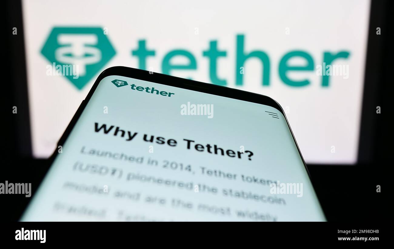Smartphone with website of crypto company Tether Operations Limited on screen in front of business logo. Focus on top-left of phone display. Stock Photo