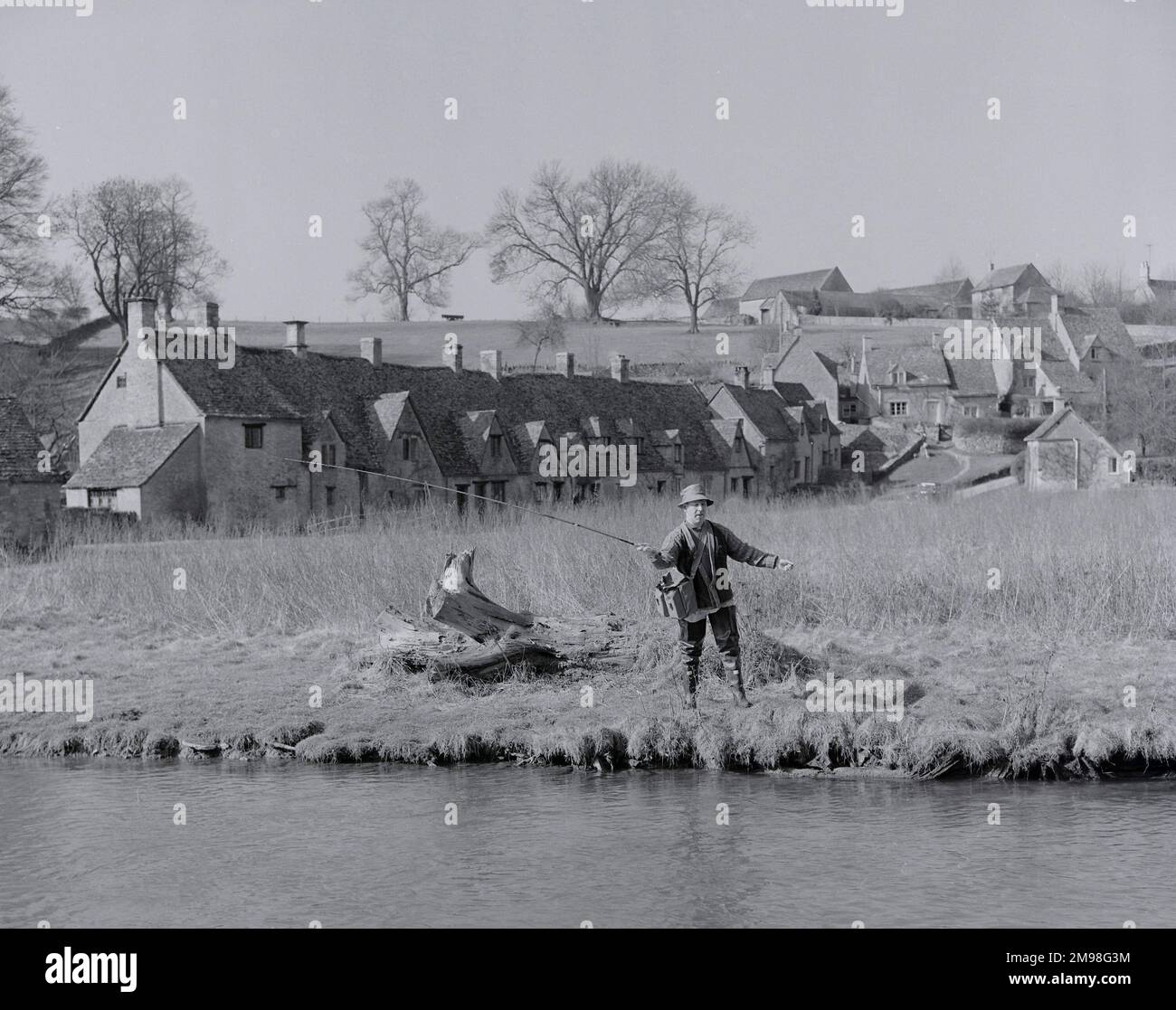 Fly Fisherman fishing in The River Coln Bibury Gloucestershire England Arlington Row Cottages in