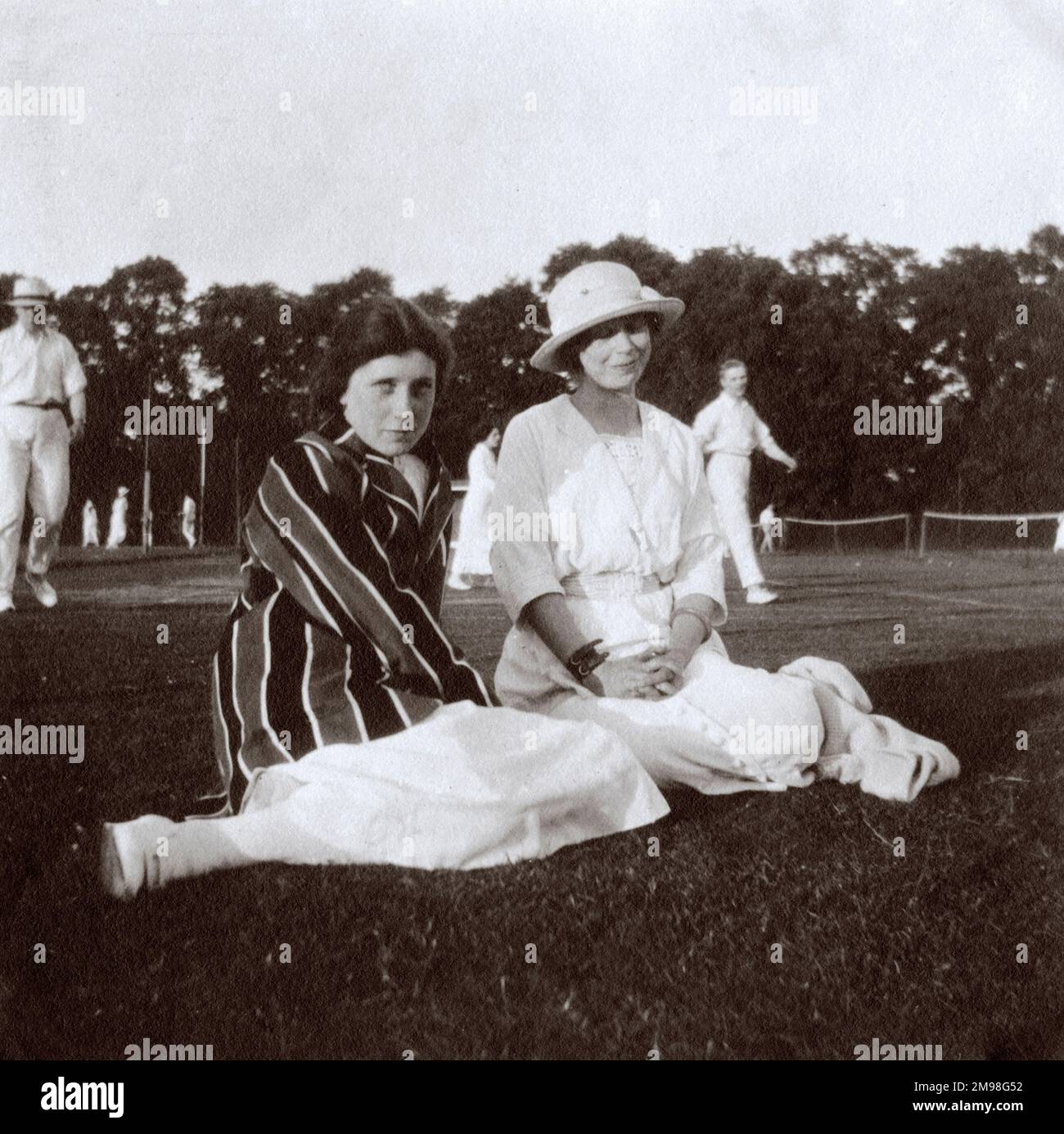 Two young women (Dorothy and Madge Hay) at Hanger Hill Tennis Club, Ealing, West London, with people playing tennis in the background. Stock Photo