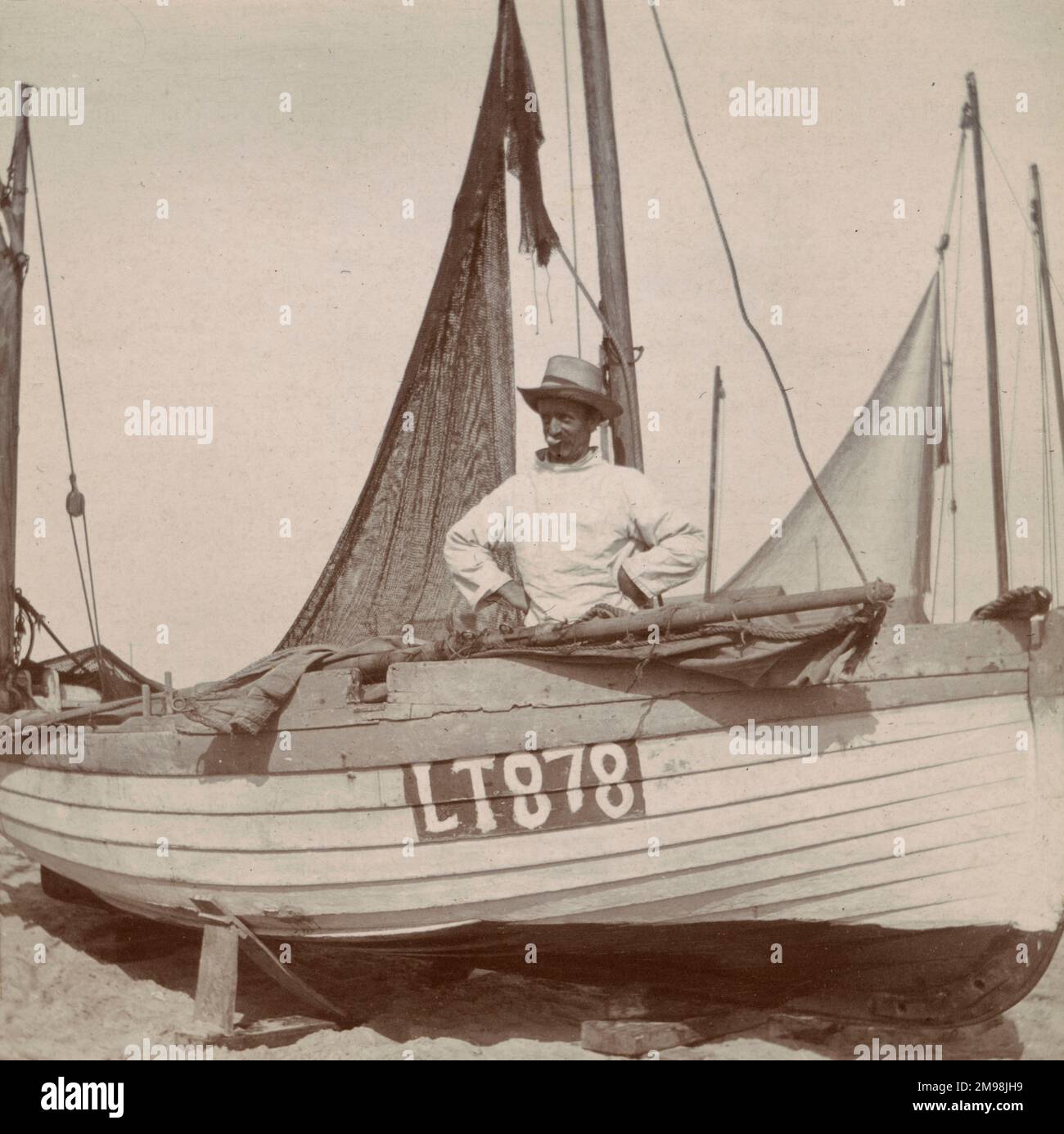 Fisherman Jimmy Peck standing inside a boat on the beach at Southwold, Suffolk, September 1907. Stock Photo