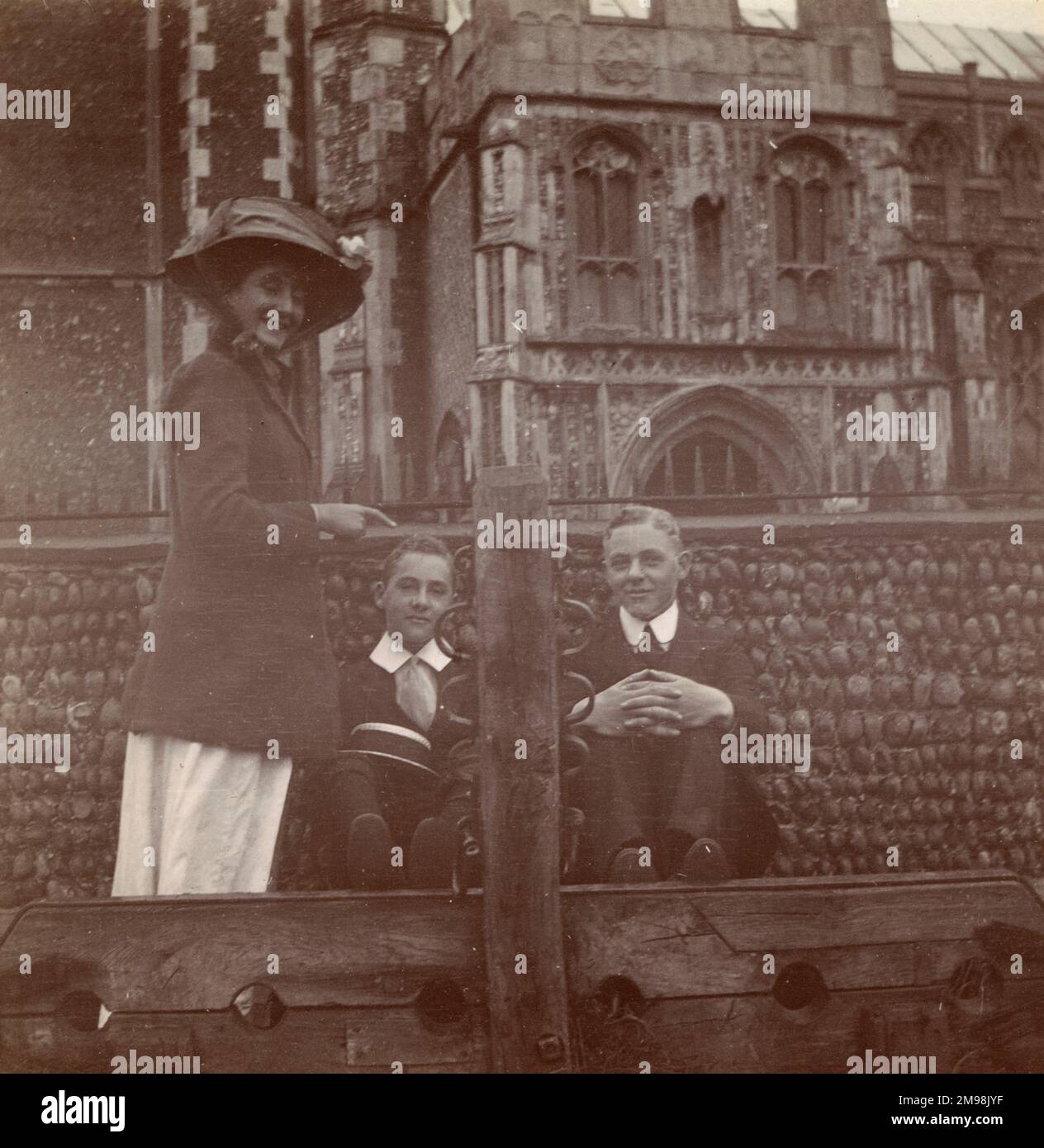 Two boys sitting behind the stocks in Southwold, Suffolk, September 1910. They are Harold and Albert Auerbach. Their sister (Lucy) points and smiles. Stock Photo