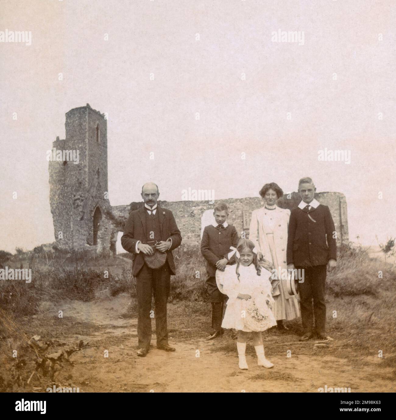 Family (Arthur, Harold, Lucy, Albert and Violet Auerbach) on a holiday outing to the village of Dunwich, Suffolk, 30 August 1908. The building is All Saints' Church, abandoned in the 1750s. By this time coastal erosion meant that the building was on the cliff edge: the tower fell in 1922. Stock Photo