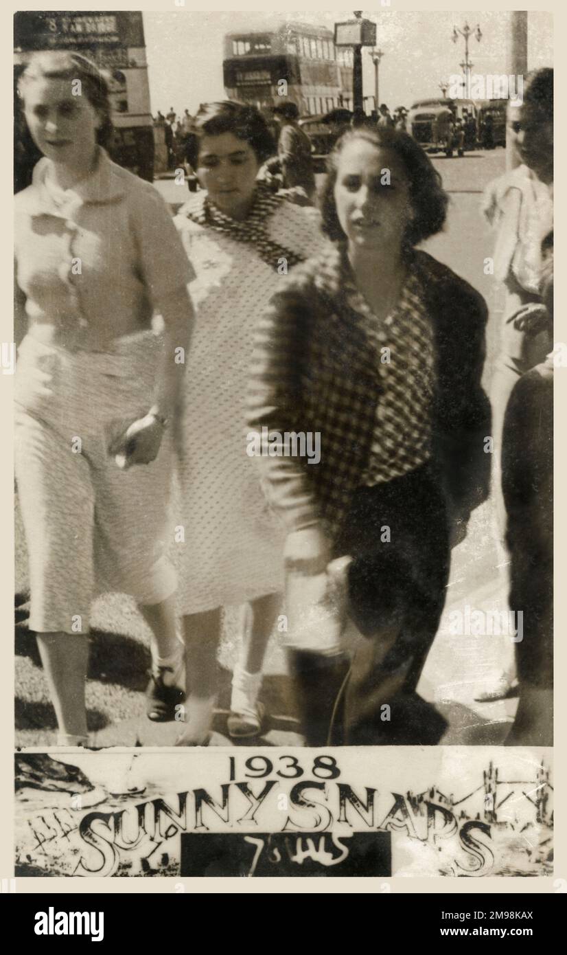 Four young women at the British seaside strolling along the front - a busy summers day. Stock Photo