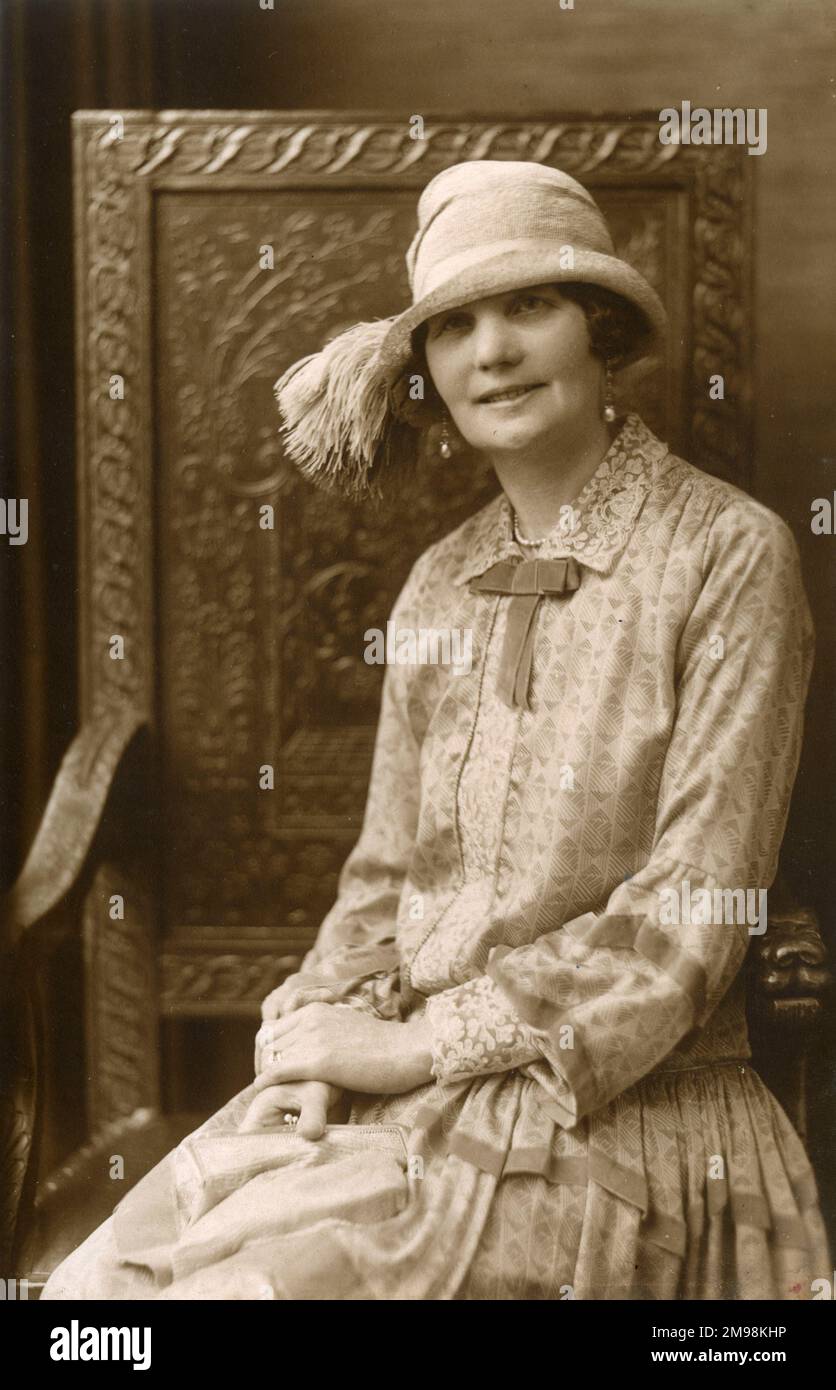 A lady ('Marion') - studio portrait (Photographer: Carl Cloud, 59a Bridge Street, Deansgate, Manchester) - wearing a very stylish blouse and hat (with tassel) seated on a large carved wooden throne. Stock Photo