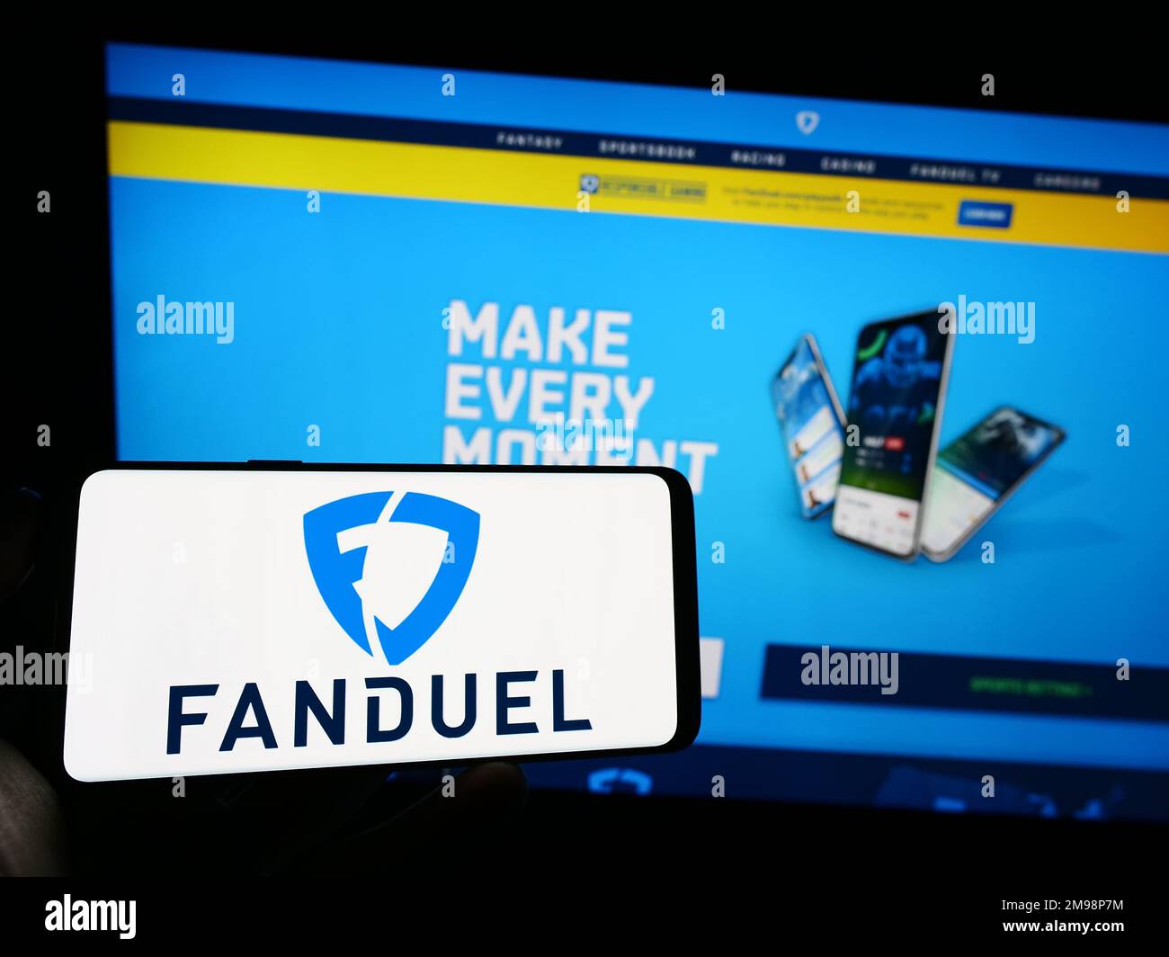 Person holding cellphone with logo of US gambling company FanDuel Inc. on screen in front of business webpage. Focus on phone display. Stock Photo