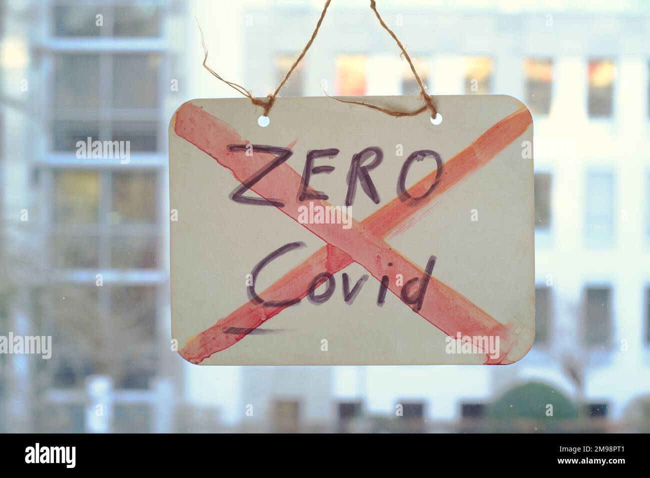 End Zero covid policy sign on window, office buildings in the back Stock Photo