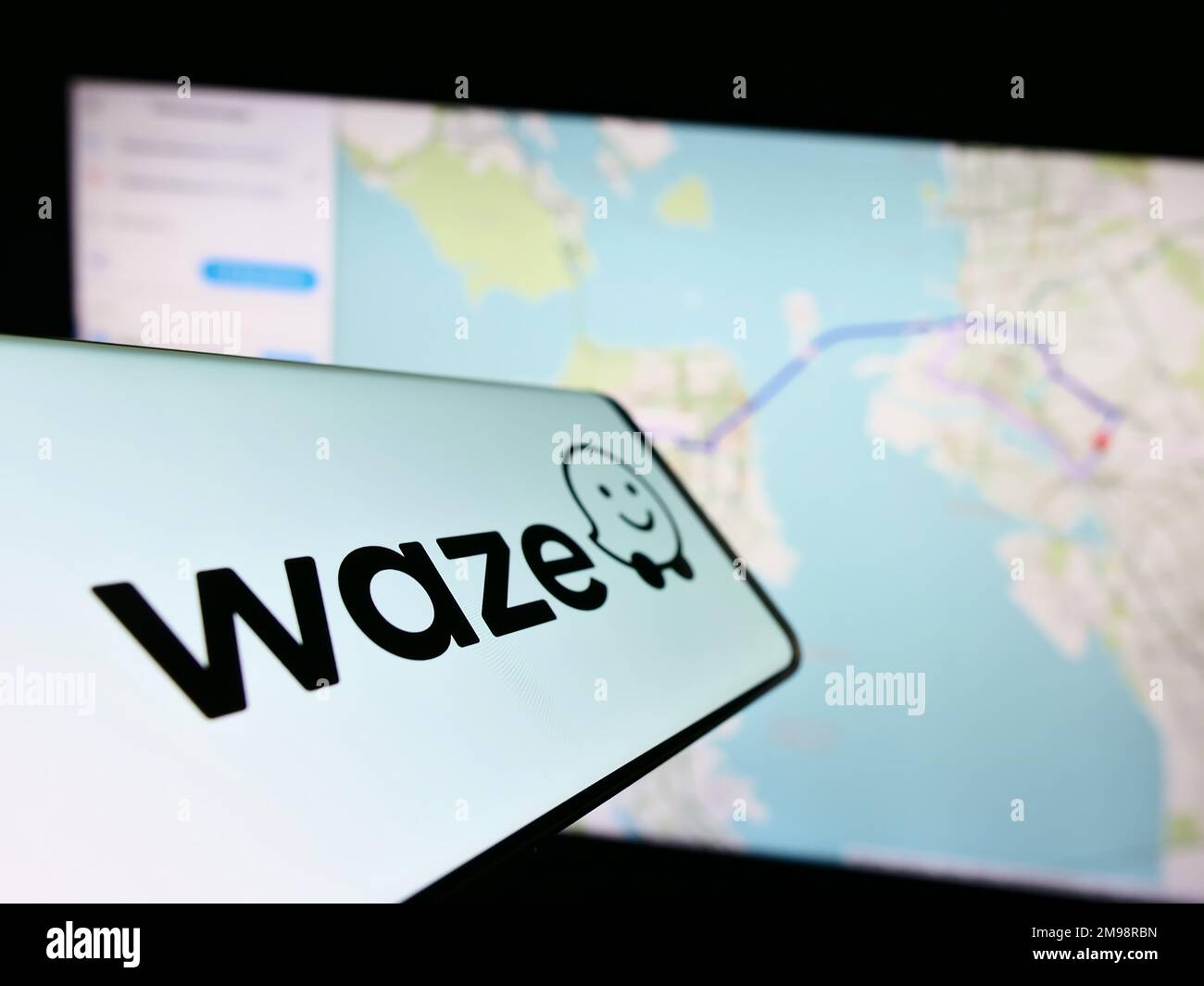 Cellphone with logo of Israeli navigation company Waze Mobile Ltd. on screen in front of business website. Focus on center-right of phone display. Stock Photo