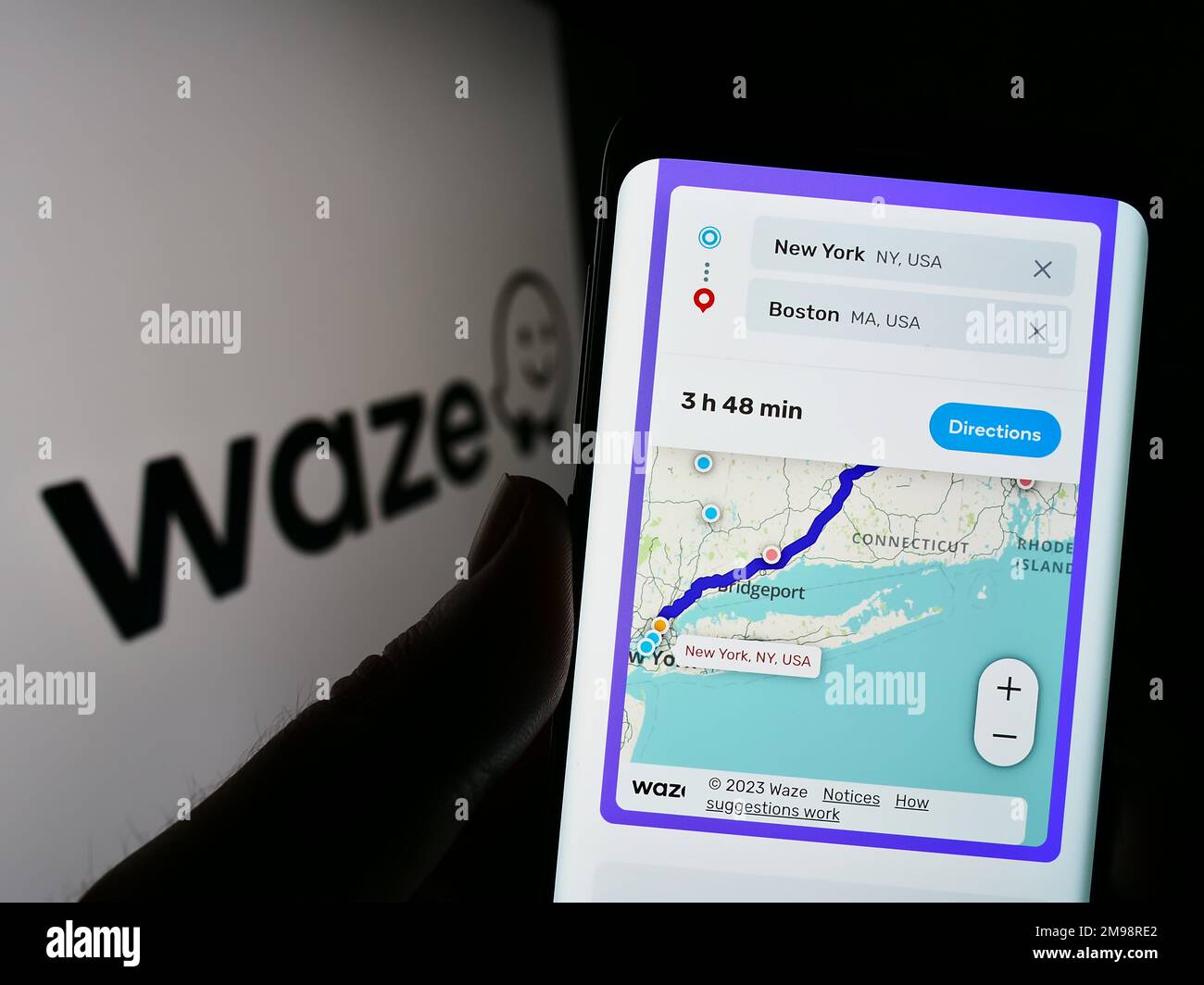 Person holding mobile phone with webpage of Israeli navigation company Waze Mobile Ltd. on screen with logo. Focus on center of phone display. Stock Photo