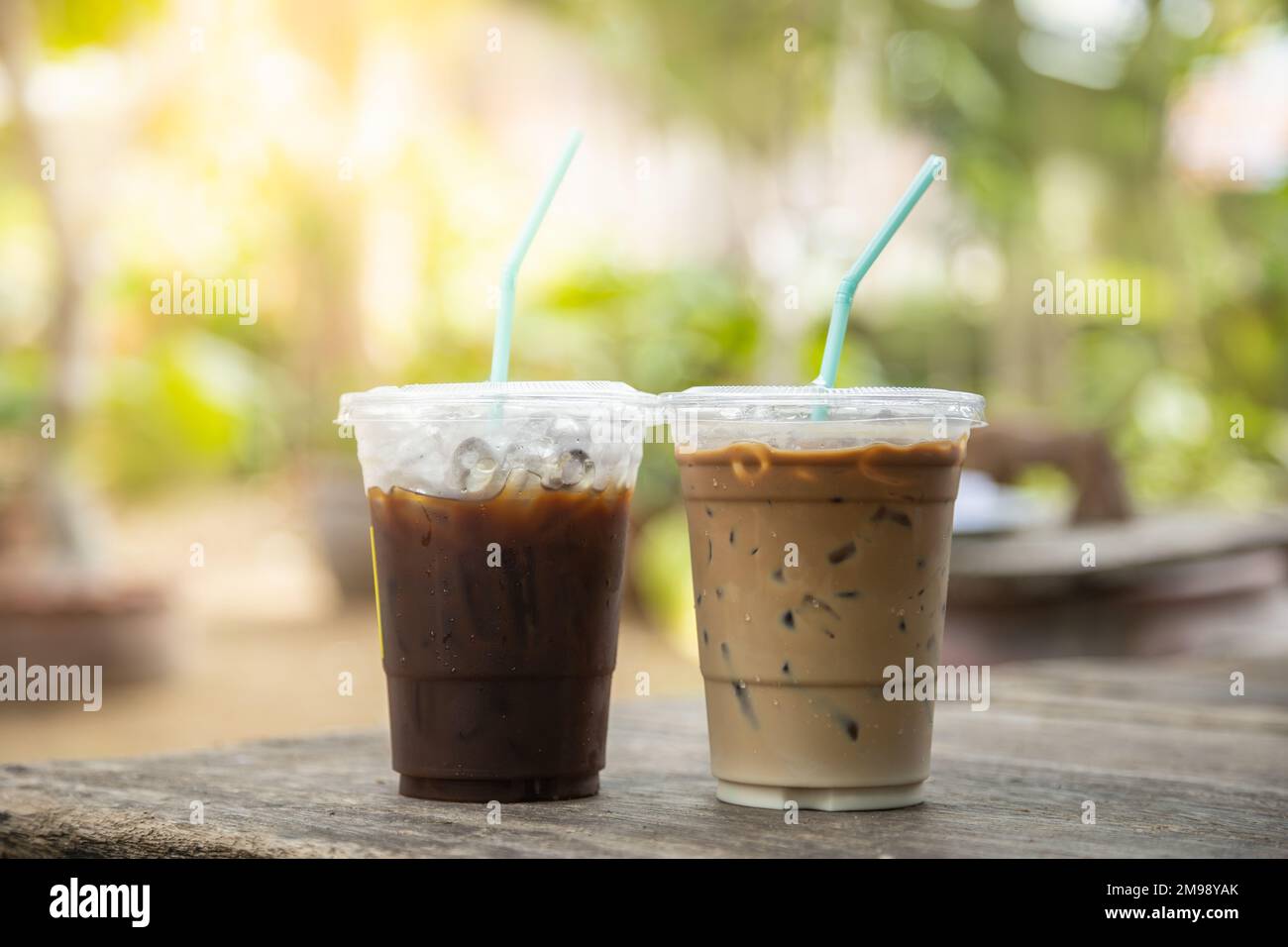 https://c8.alamy.com/comp/2M98YAK/closeup-of-takeaway-plastic-cup-of-iced-black-coffee-americano-and-coffee-latte-on-wooden-table-with-green-nature-background-2M98YAK.jpg